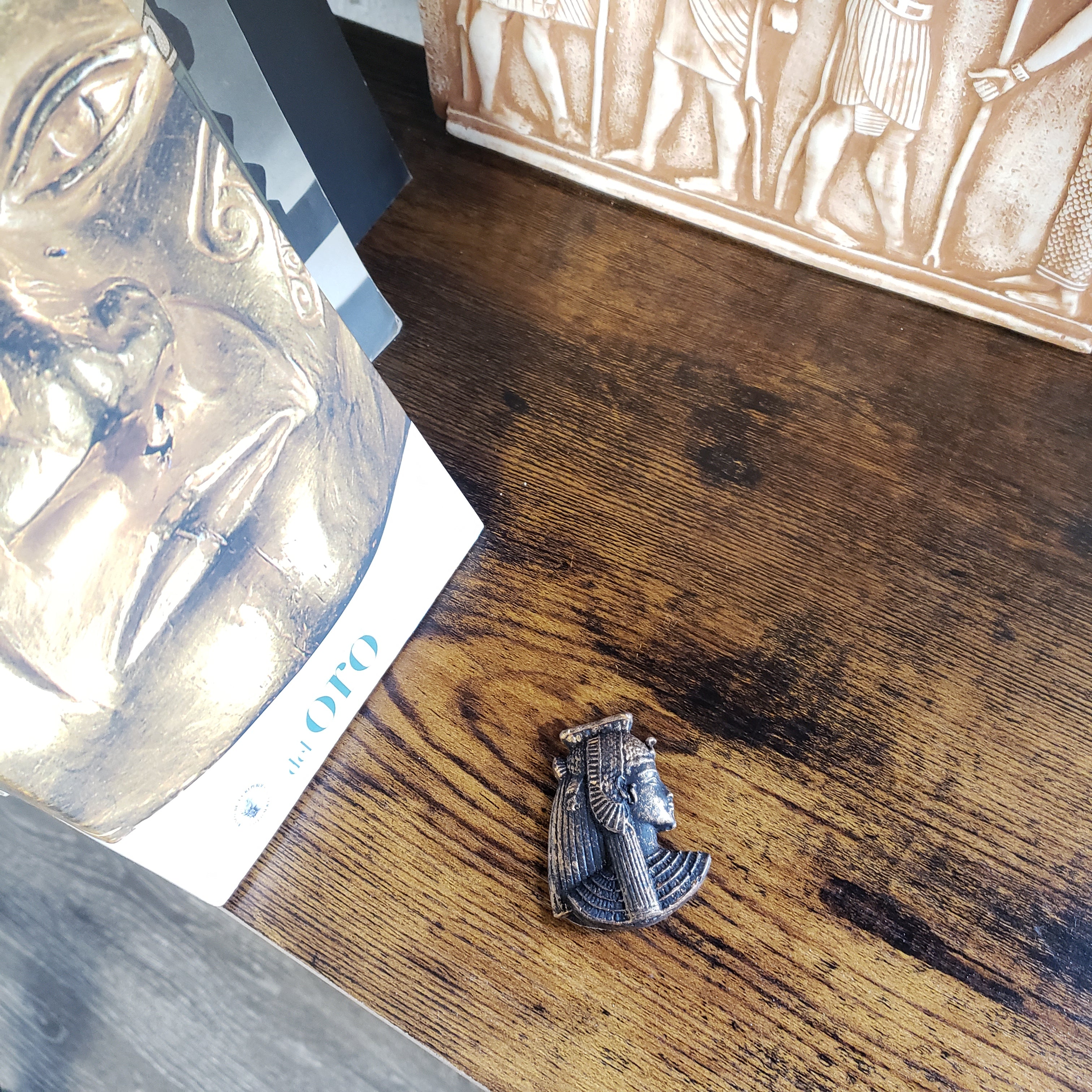 Decorative figurine on a wooden surface with ancient Egyptian-themed books.