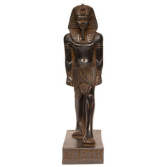 An ancient Egyptian pharaoh statue in a dark finish, standing on a rectangular base with hieroglyphic details, isolated on a white background.