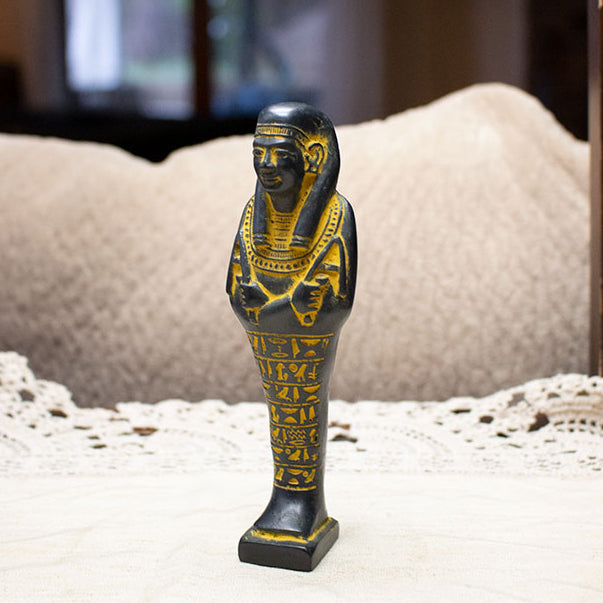 Decorative statue of an Egyptian mummy on a lace tablecloth with a blurred background