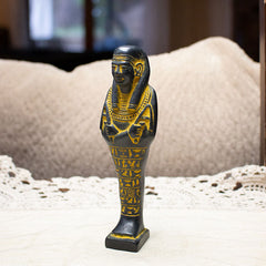 Decorative statue of an Egyptian mummy on a lace tablecloth with a blurred background