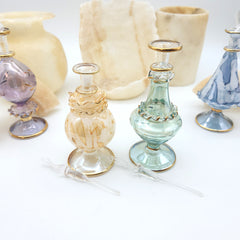 Decorative glass bottles with gold accents on a white surface