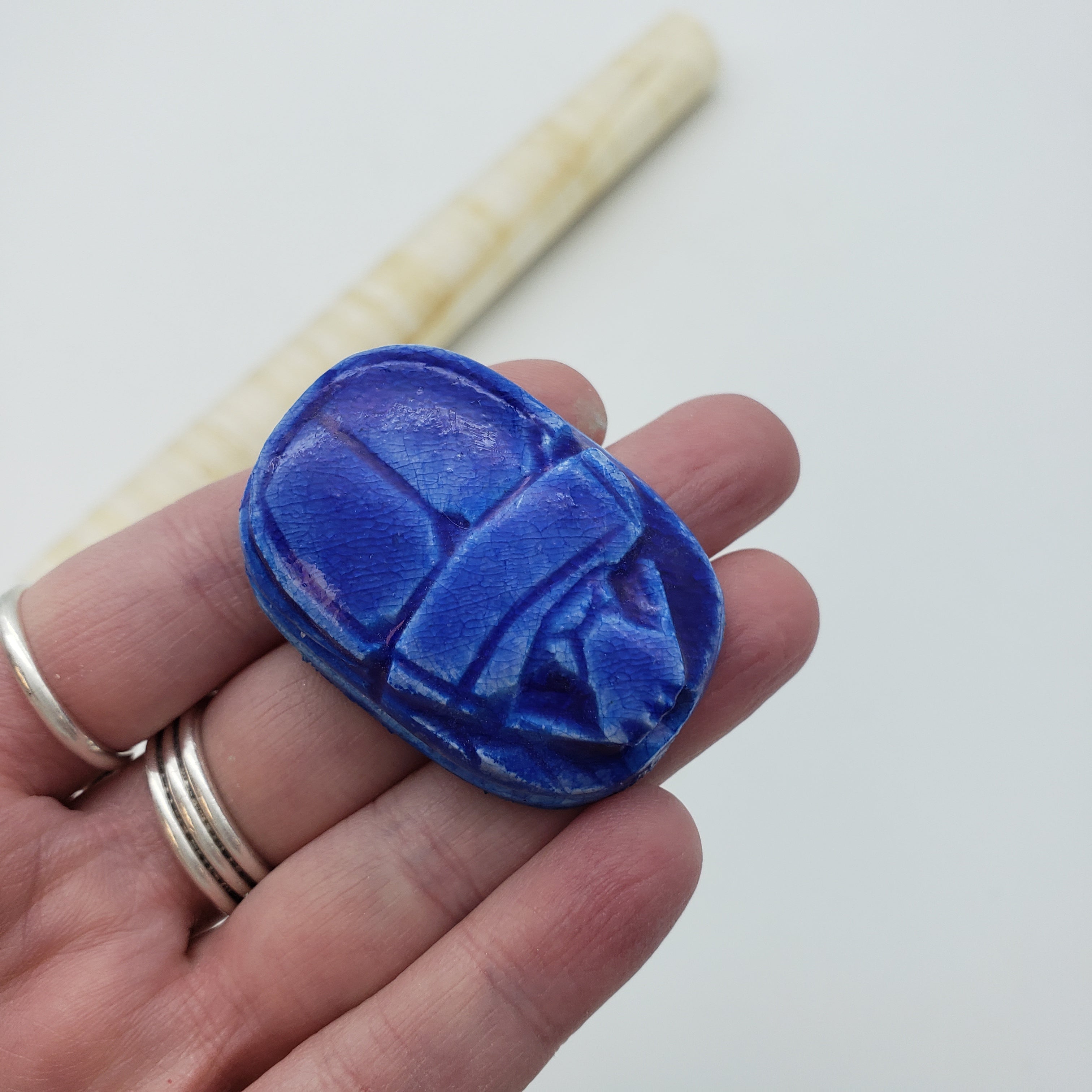 Hand holding a blue decorative item with a white background