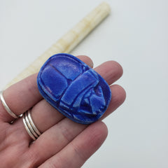 Hand holding a blue decorative item with a white background