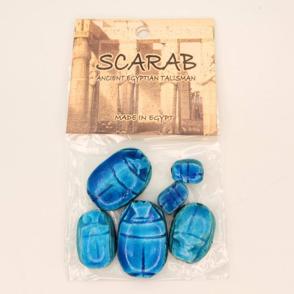 Blue scarab beetles in clear packaging with 'Scarab' and 'Made in Egypt' text on a beige background