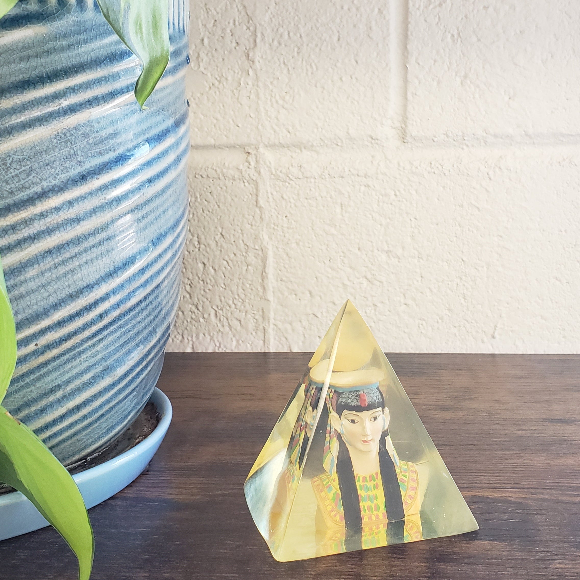 Decorative wall art with a woman's face on a wooden panel next to a textured white wall.