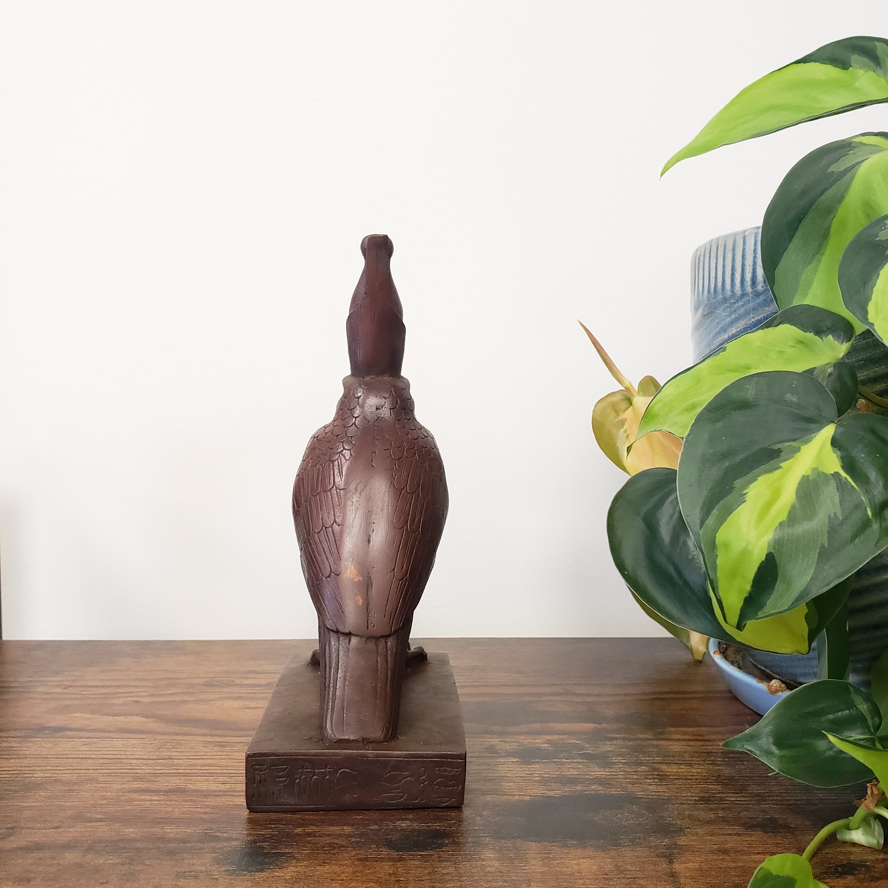 Egyptian falcon-god Horus sculpture of a duck on a wooden surface with a plant in the background