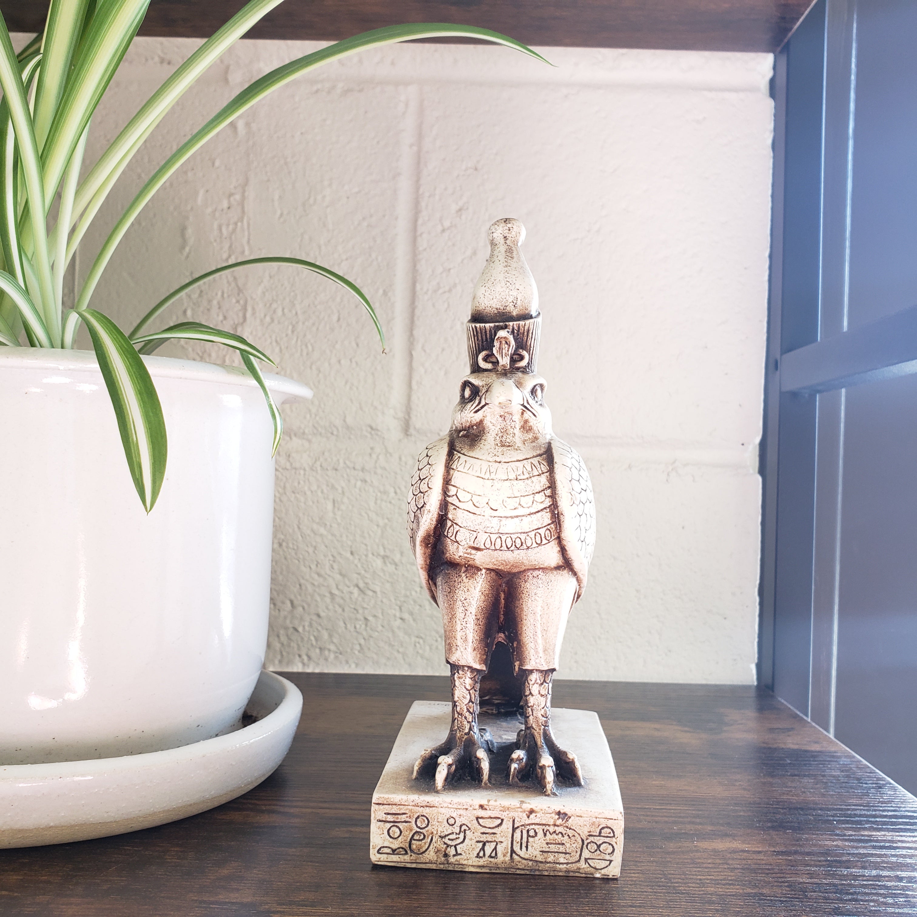 Egyptian falcon-god Horus statue of a warrior on a pedestal with a plant in the foreground
