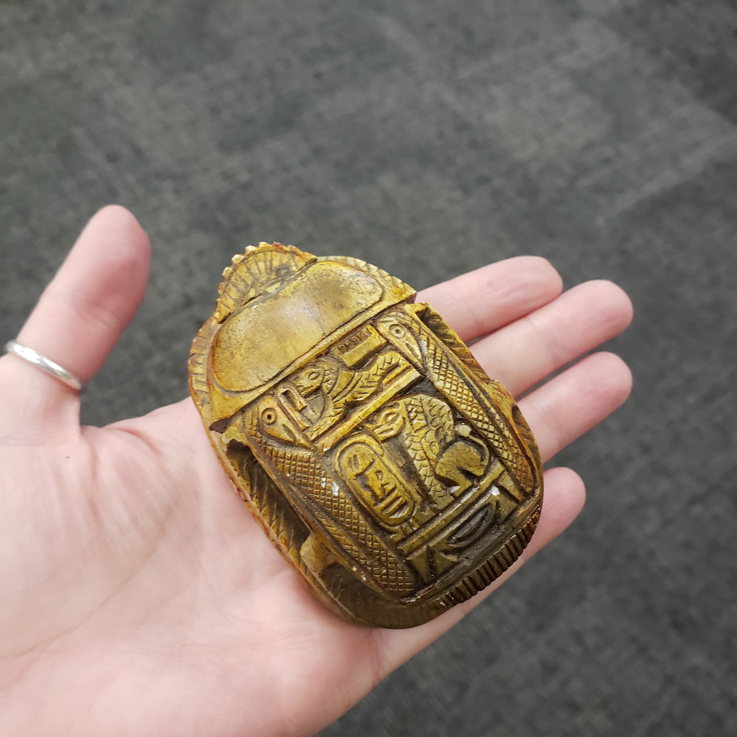 scarab statue decorative object with intricate patterns held in a hand against a dark background