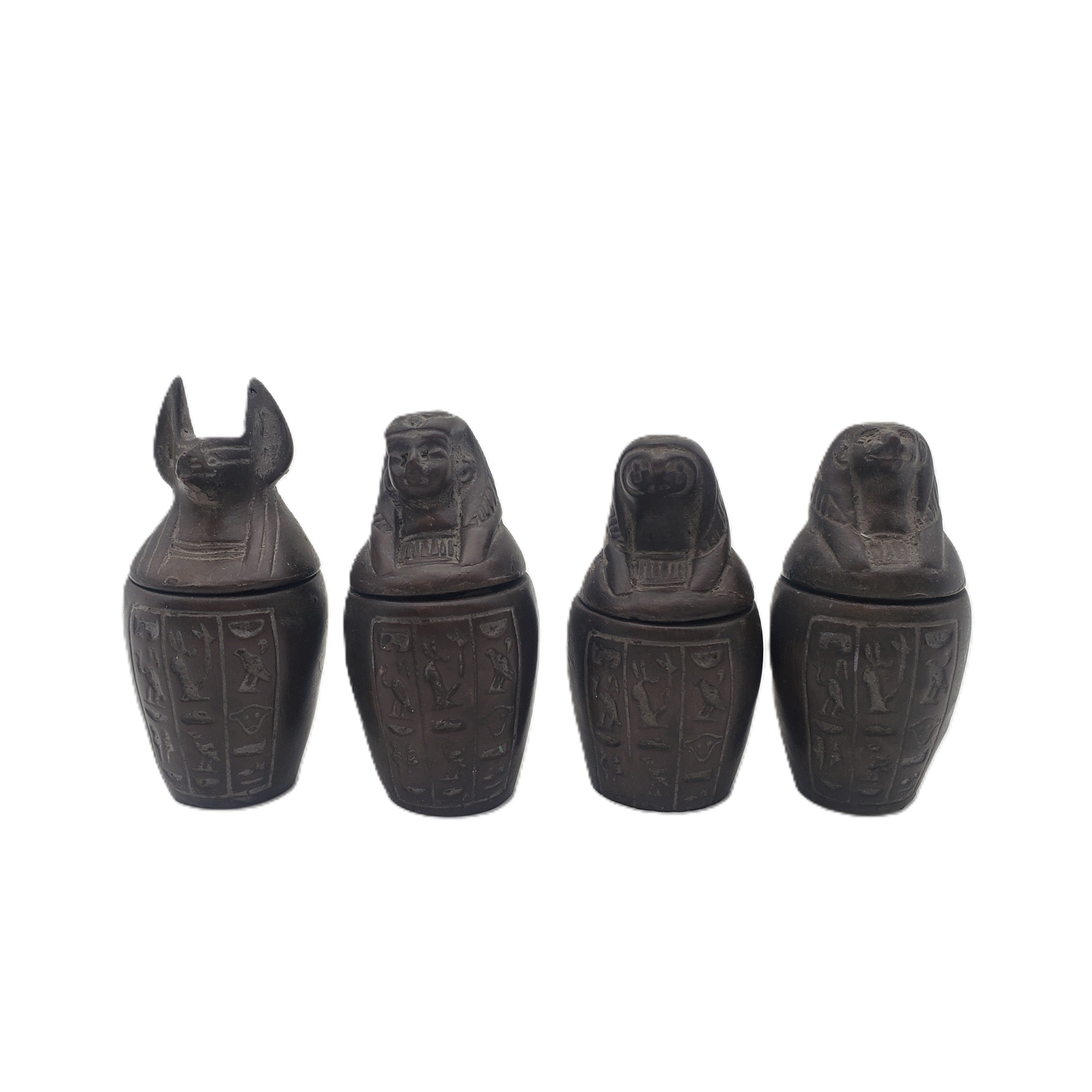 Four black decorative canopic jars with hieroglyphic designs on a white background