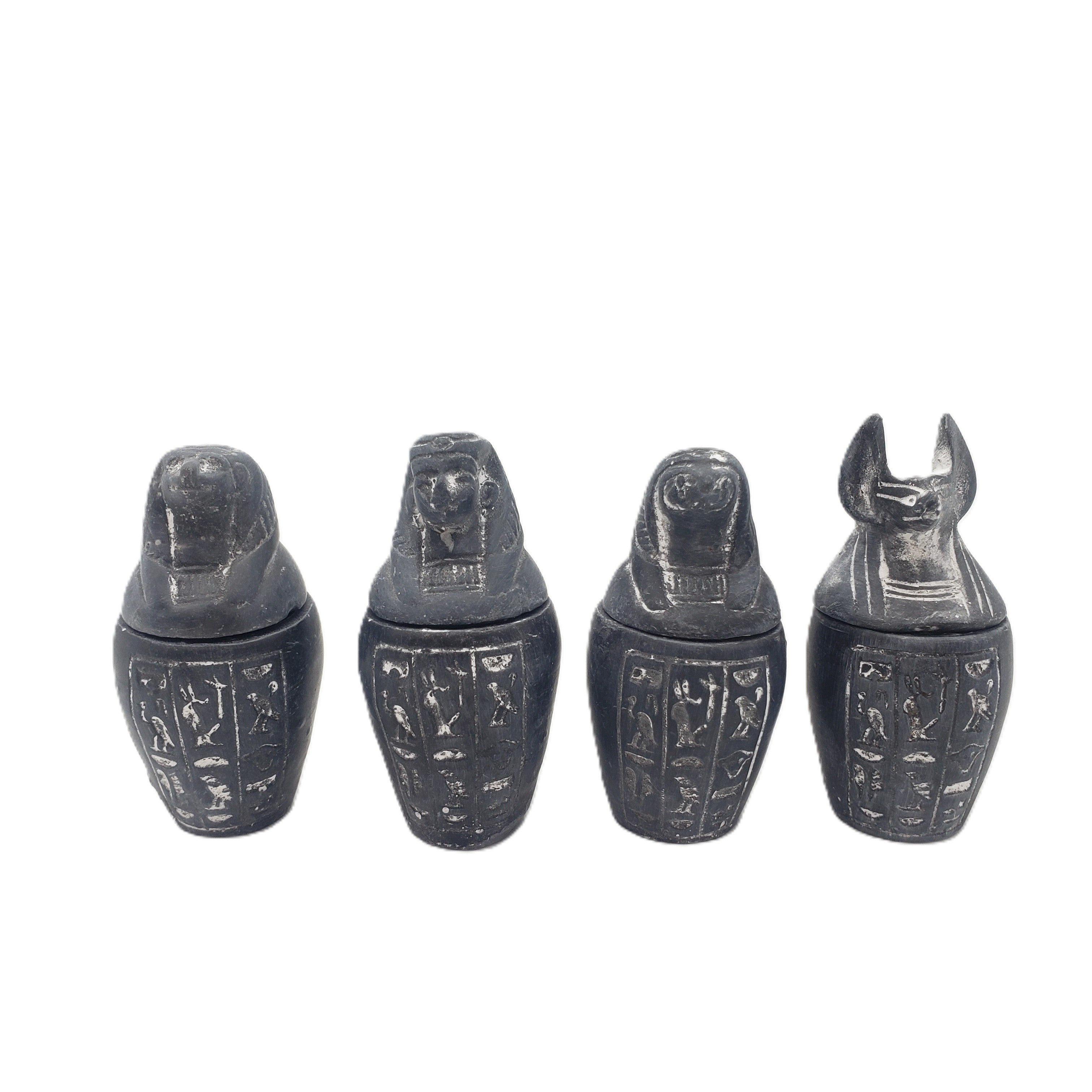 Four black  canopic jars with hieroglyphic designs on a white background
