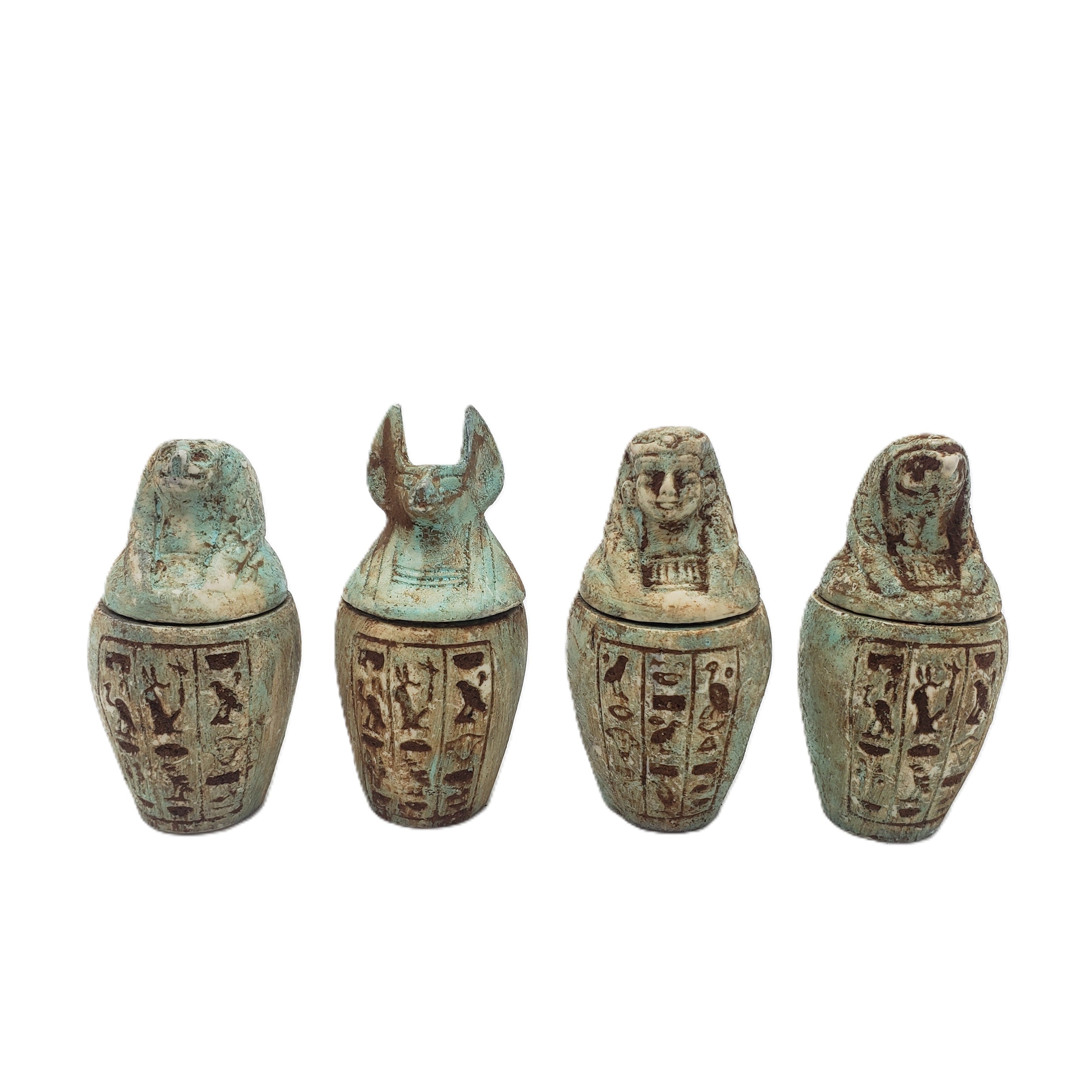 Set of four ancient Egyptian-style canopic jars with hieroglyphic designs on a white background.