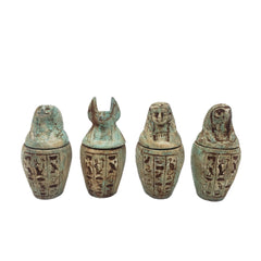 Set of four ancient Egyptian-style canopic jars with hieroglyphic designs on a white background.