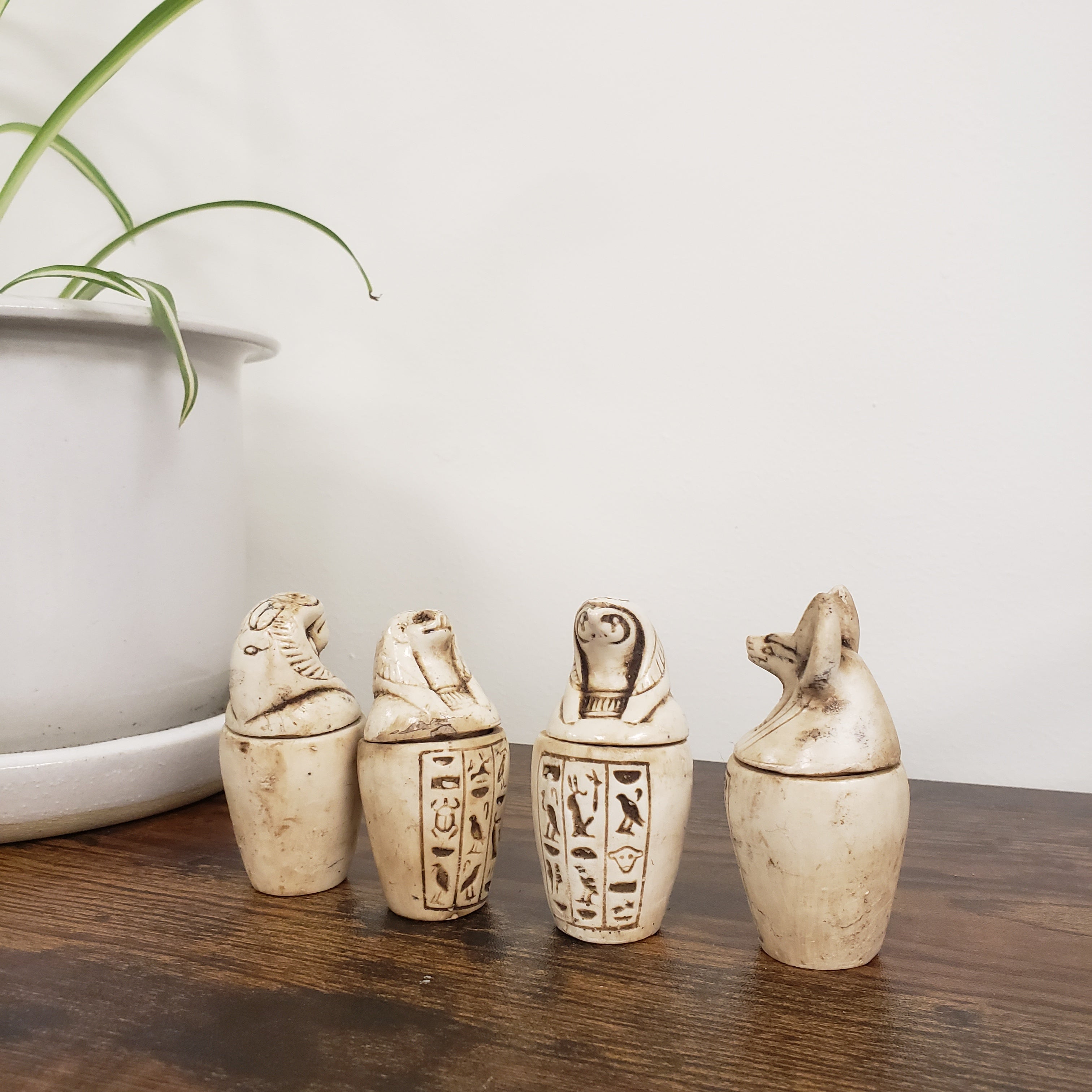 Set of canopic jar statues with hieroglyphic designs on a wooden surface.