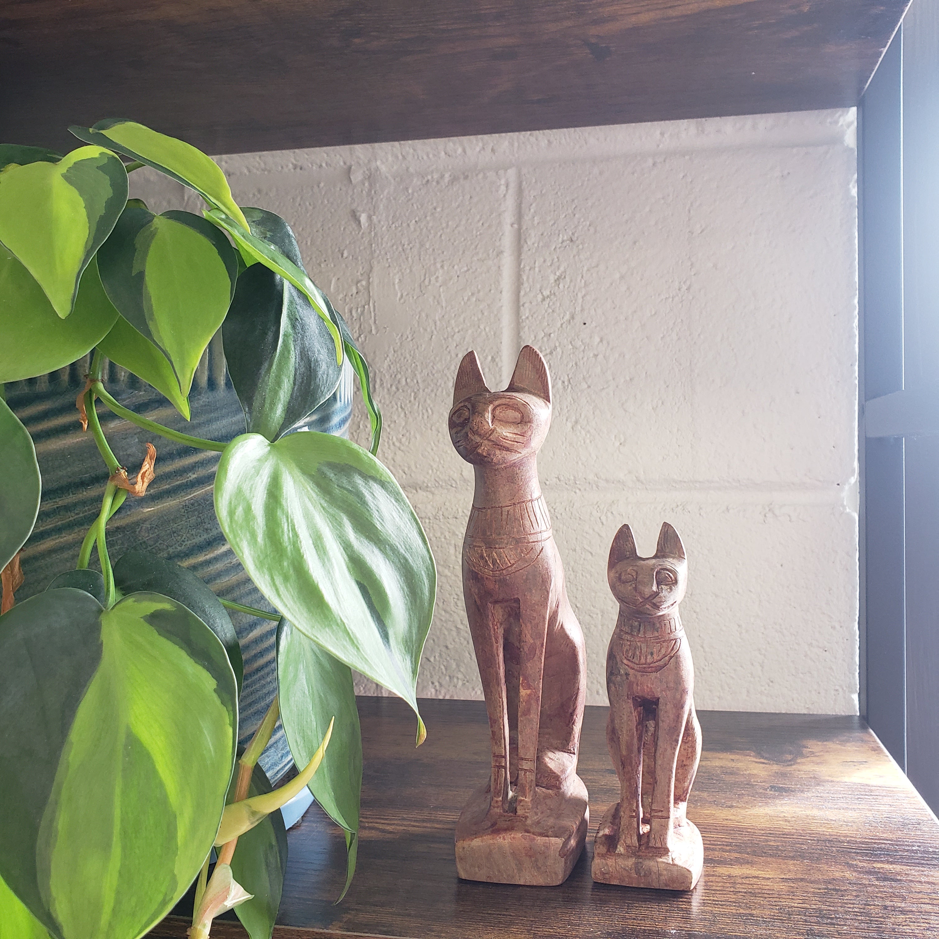 stone statues on a shelf with a plant in the foreground