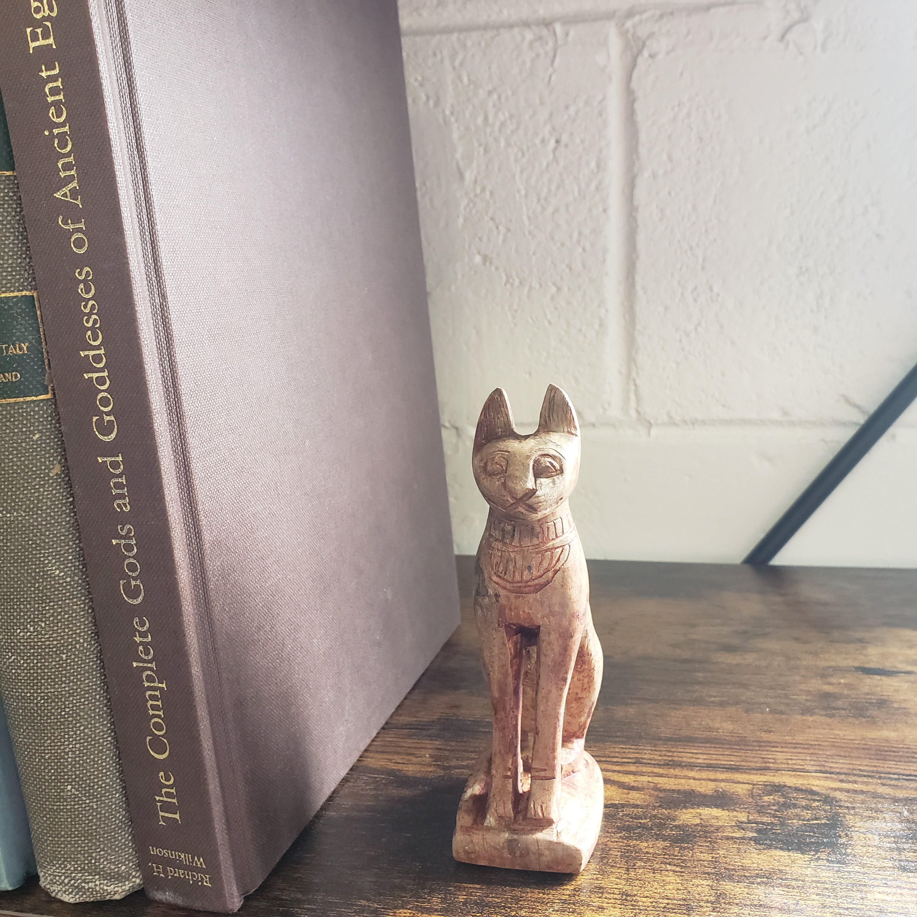 stone cat-shaped object on top of a book titled 'The Complete Gods and Goddesses of Ancient Egypt'.
