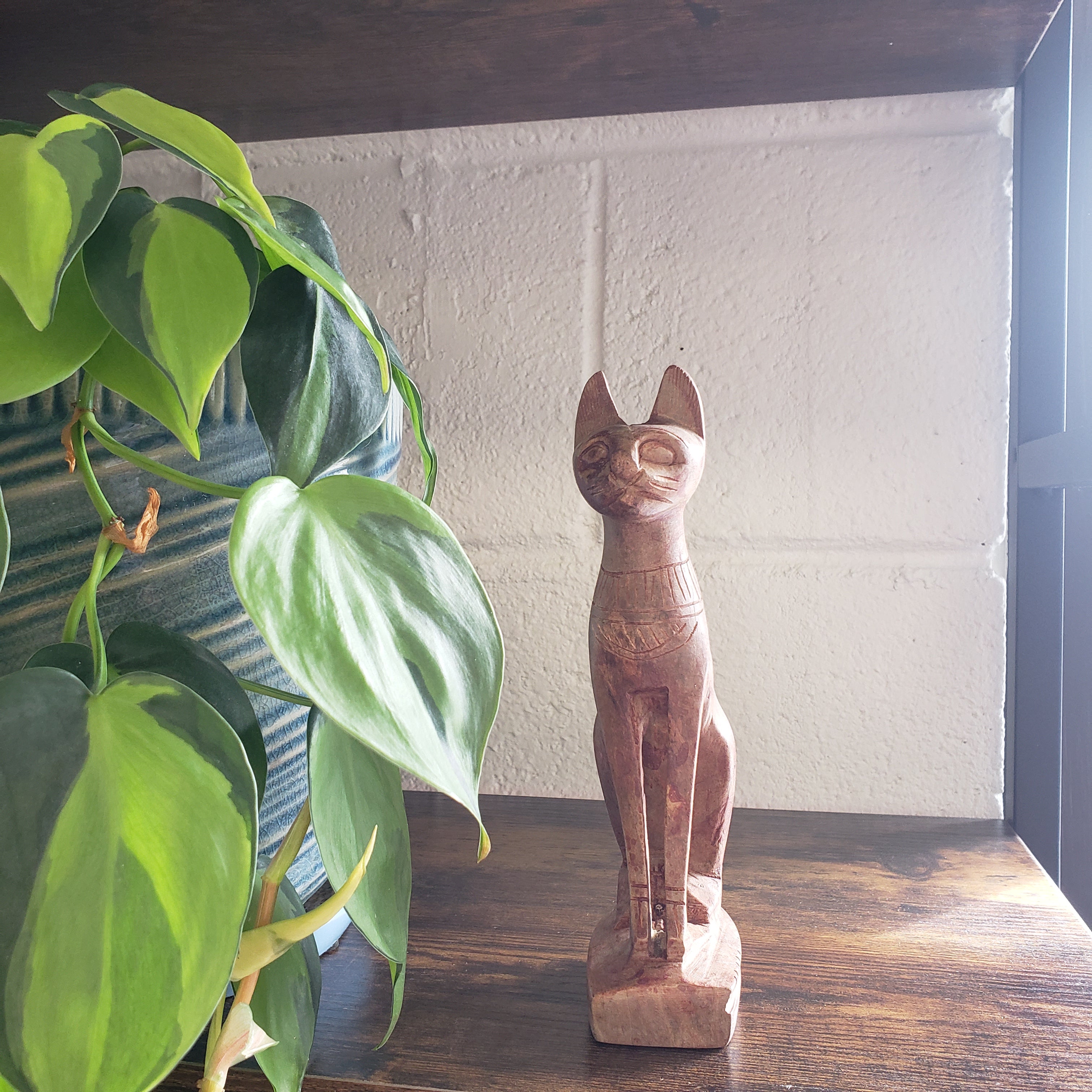 stone sculpture of a cat with green leaves in the foreground