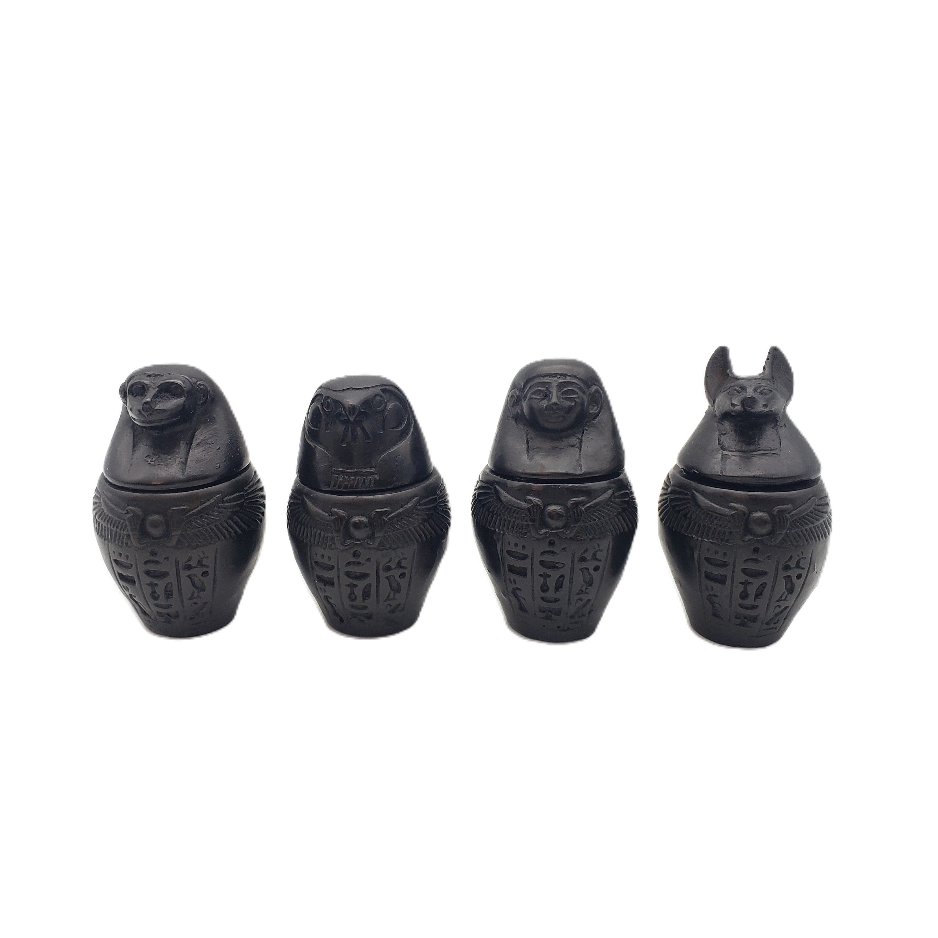 Four black decorative items resembling ancient Egyptian canopic jars on a white background
