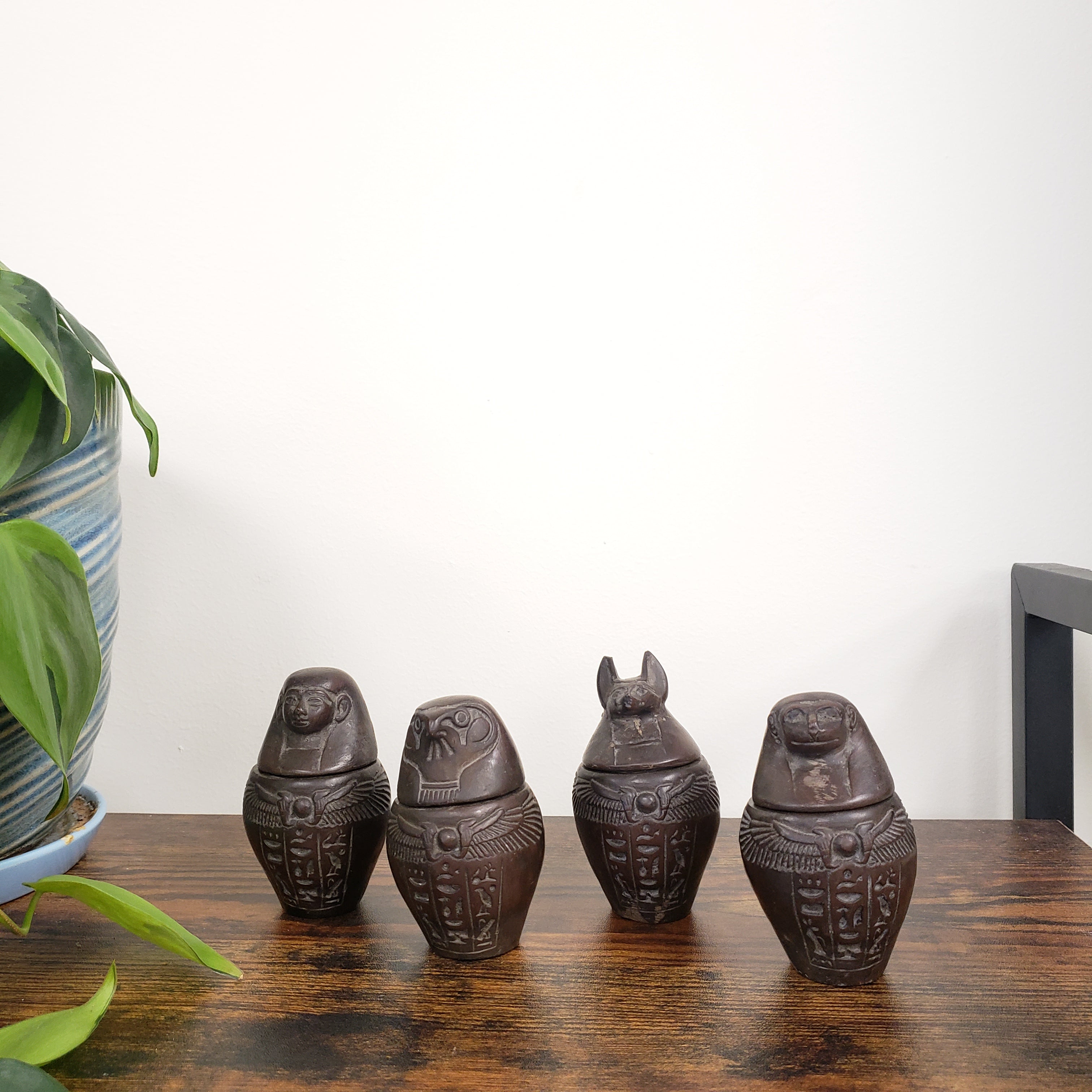Decorative Egyptian-style canopic jars on a wooden surface.