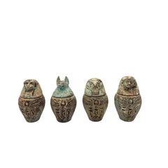 Four Egyptian-style canopic jars with animal heads on a white background