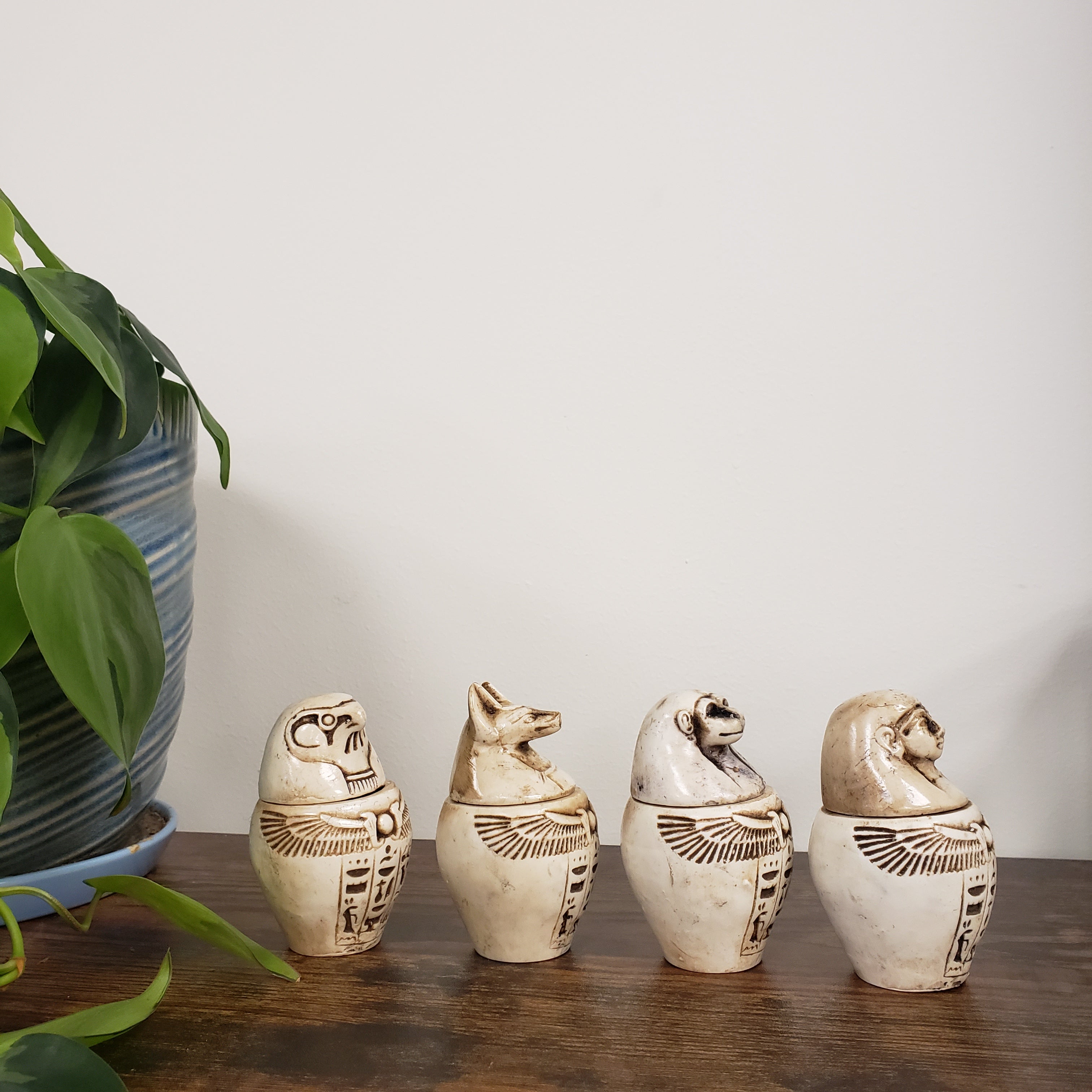 Decorative Egyptian-style canopic jars figurines against a neutral background