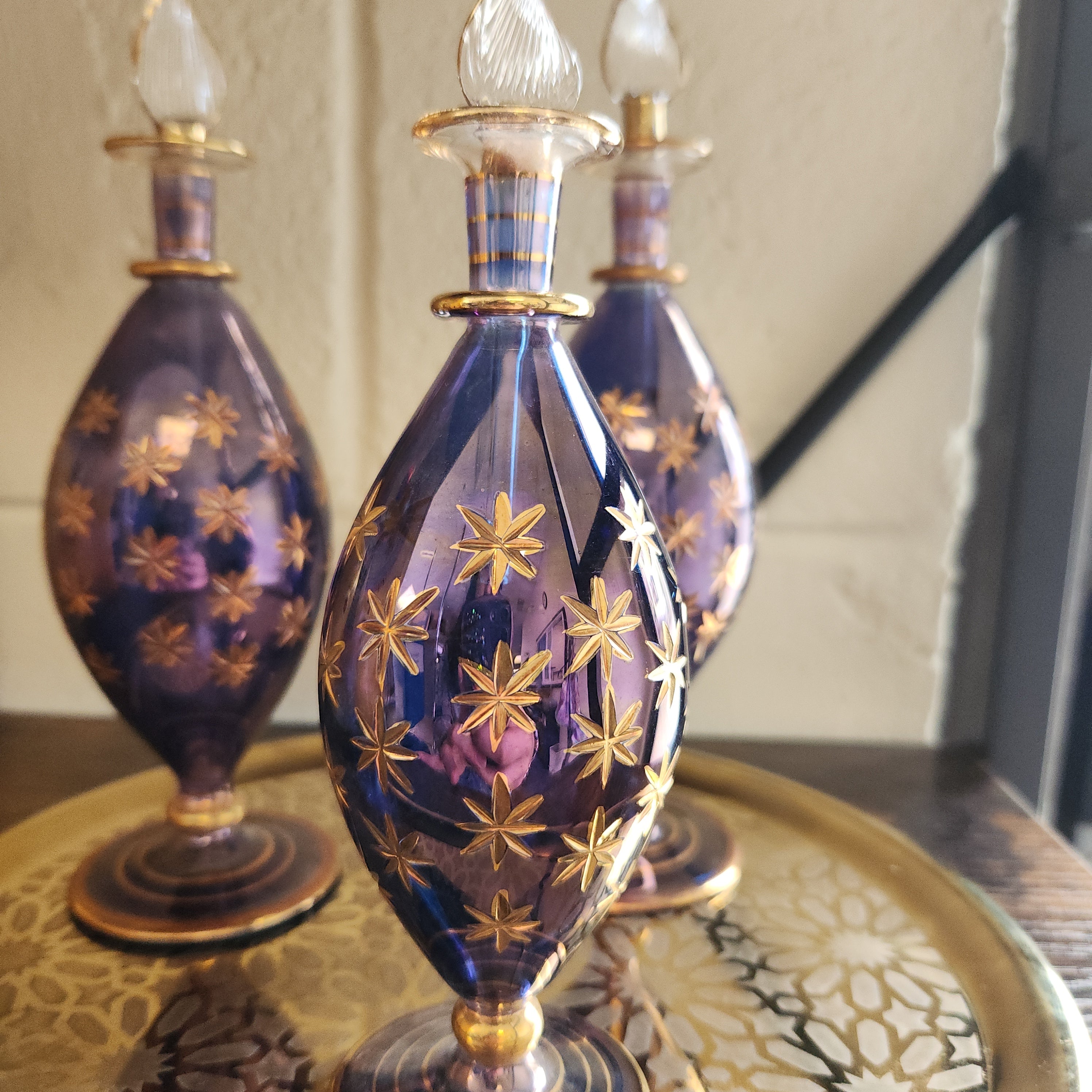 Decorative glass bottle with gold star patterns on a reflective surface