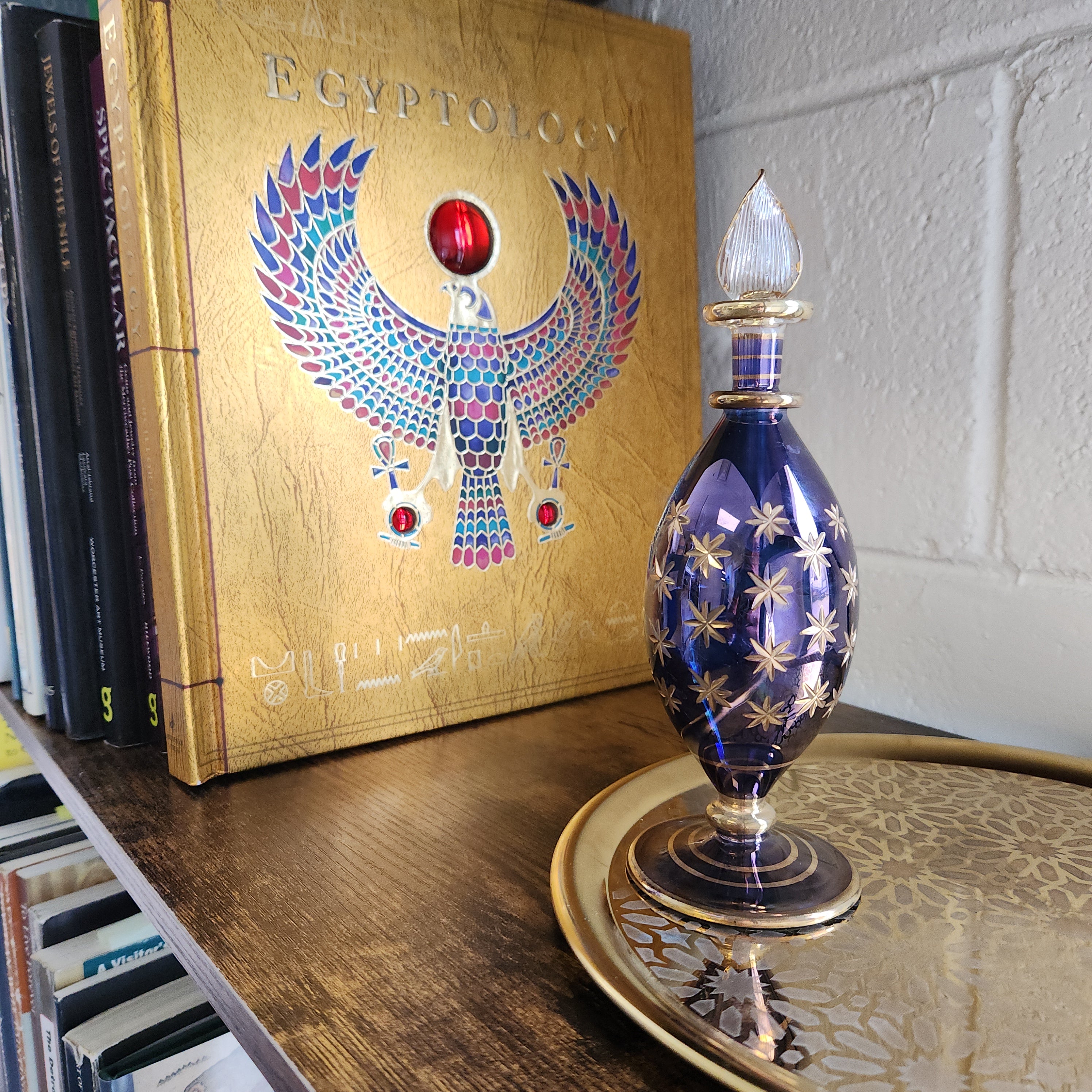 Decorative blue glass perfume bottle on a book with an Egyptian design
