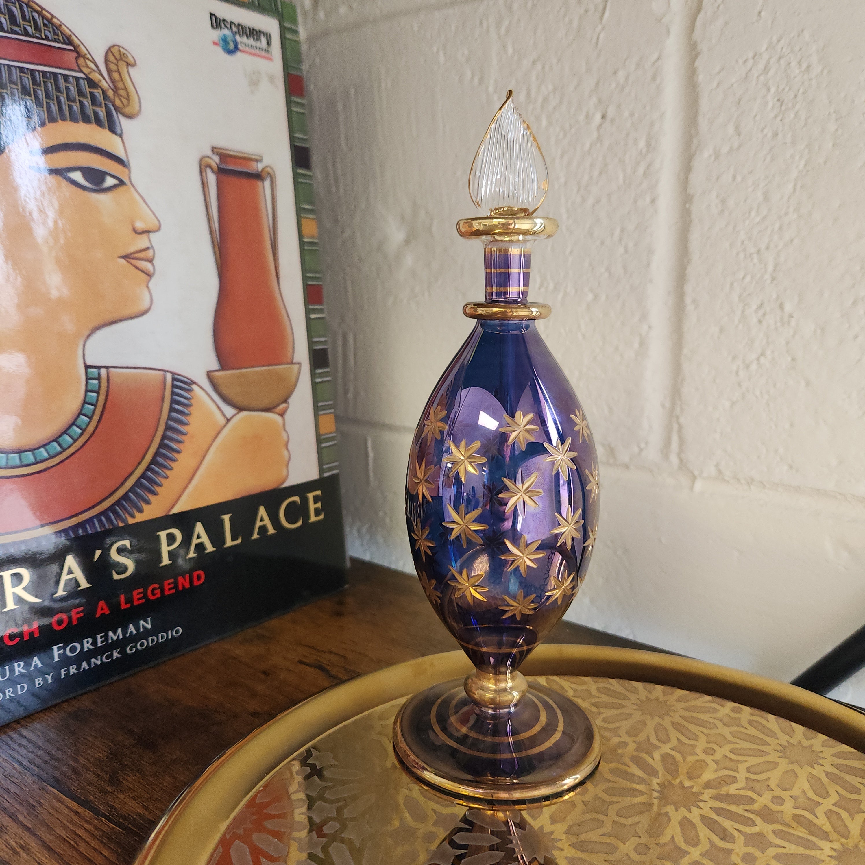Decorative blue and gold object on a table with a book titled 'Ra's Palace' in the background.