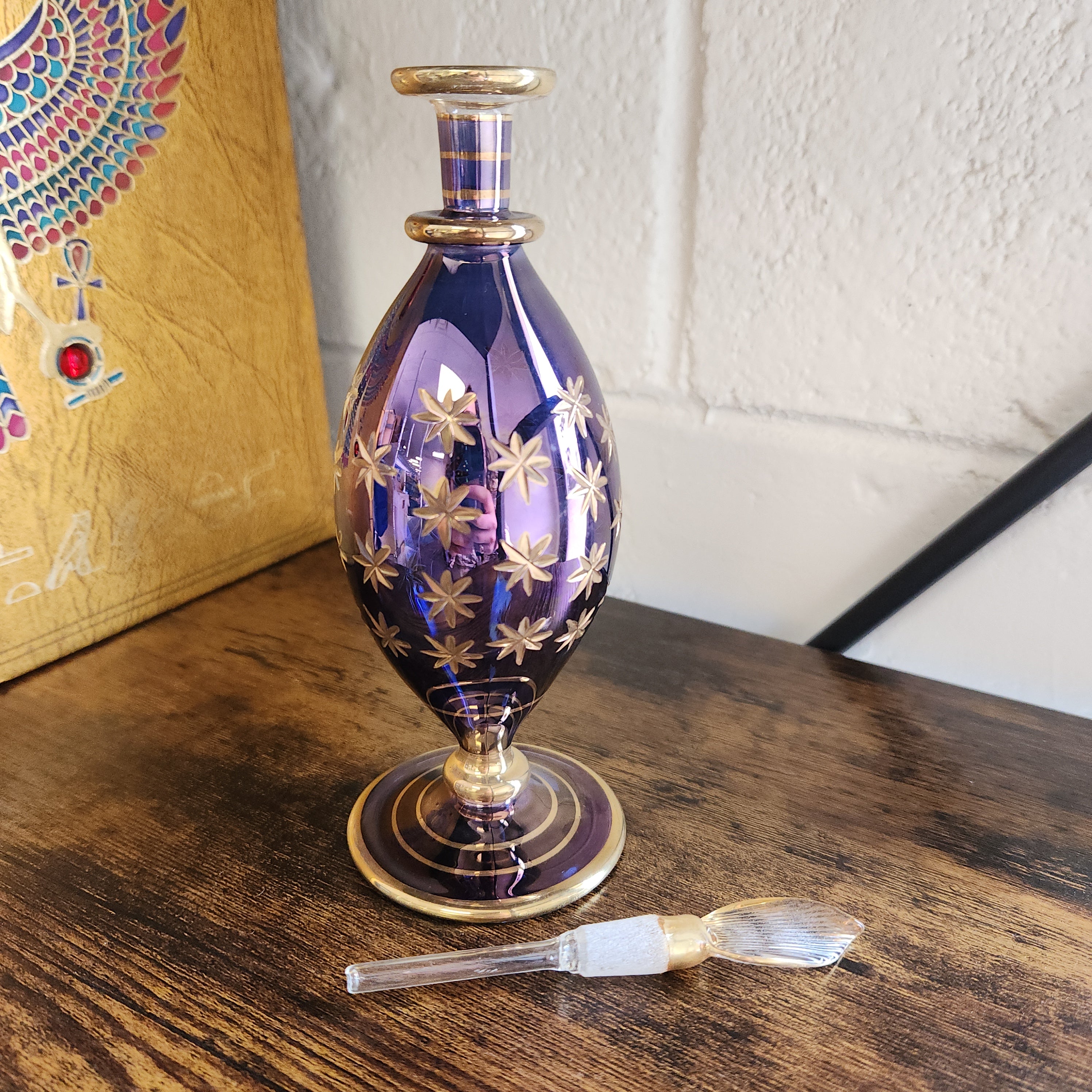 Decorative purple glass bottle with gold accents on a wooden surface