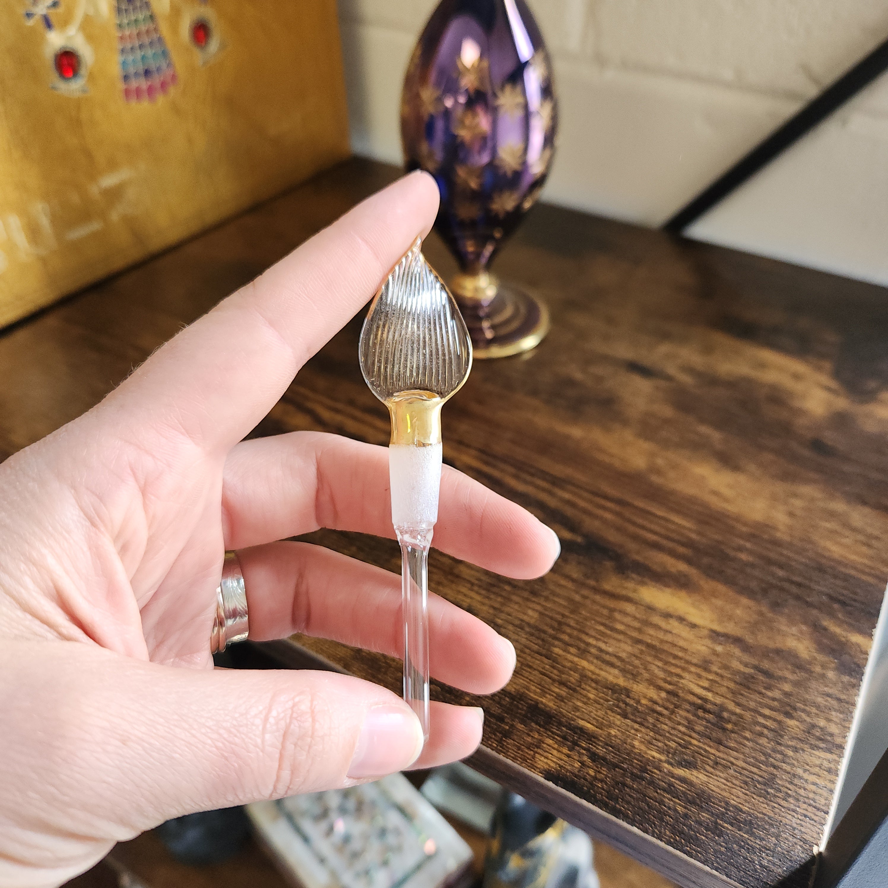 Hand holding a decorative glass perfume bottle with a blurred background