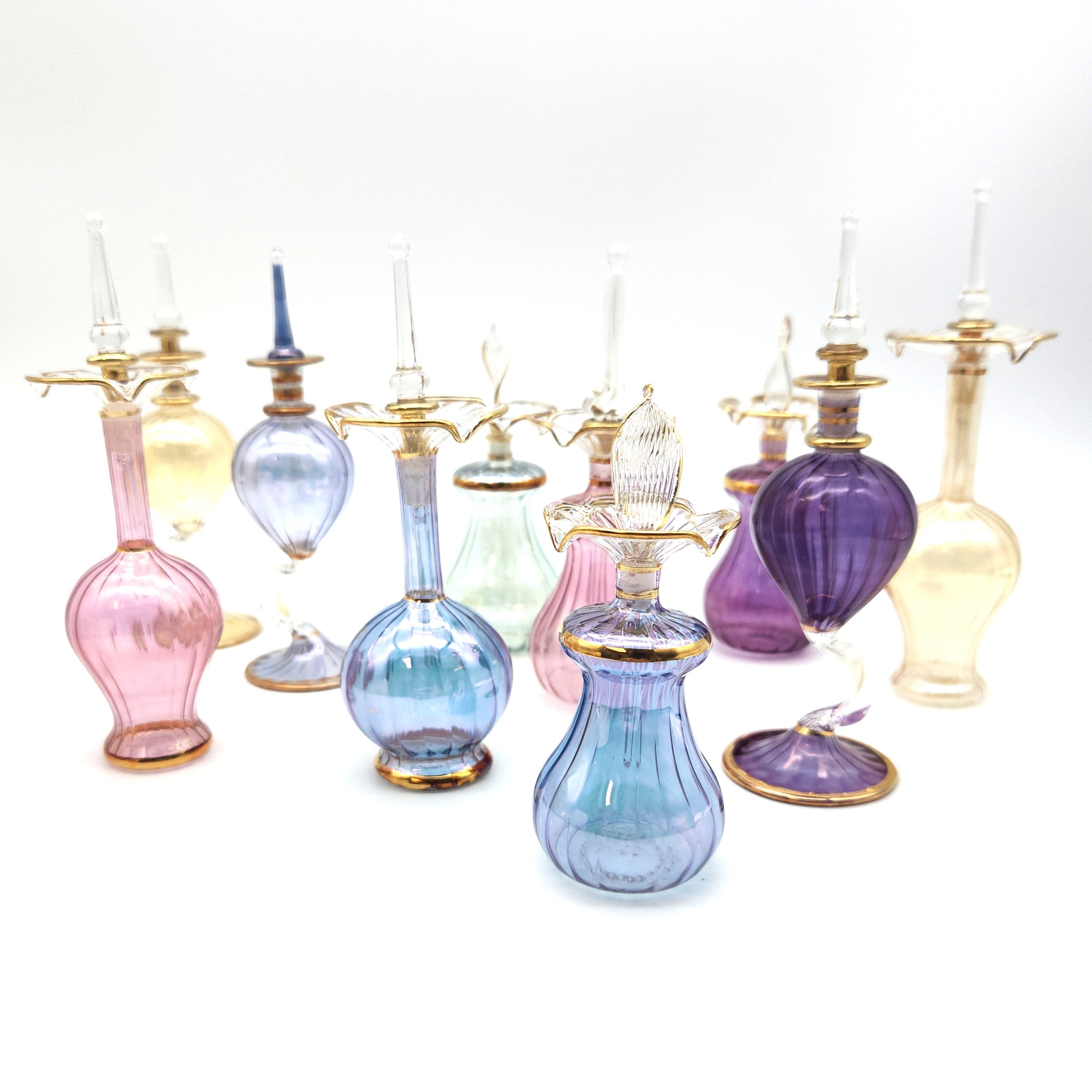 Collection of colorful glass bottles with gold accents on a white background