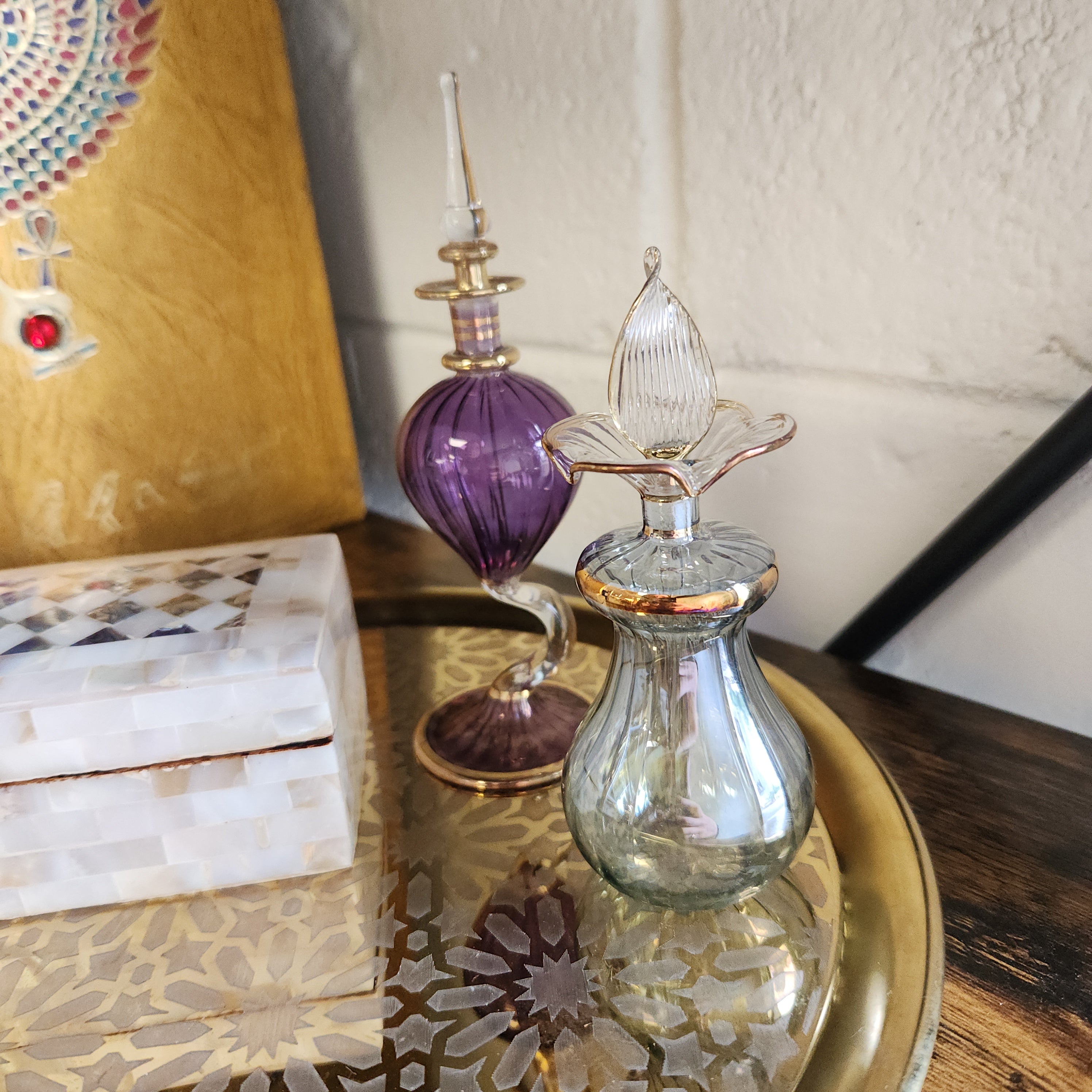 Decorative glass bottle with purple and gold elements on a wooden surface.