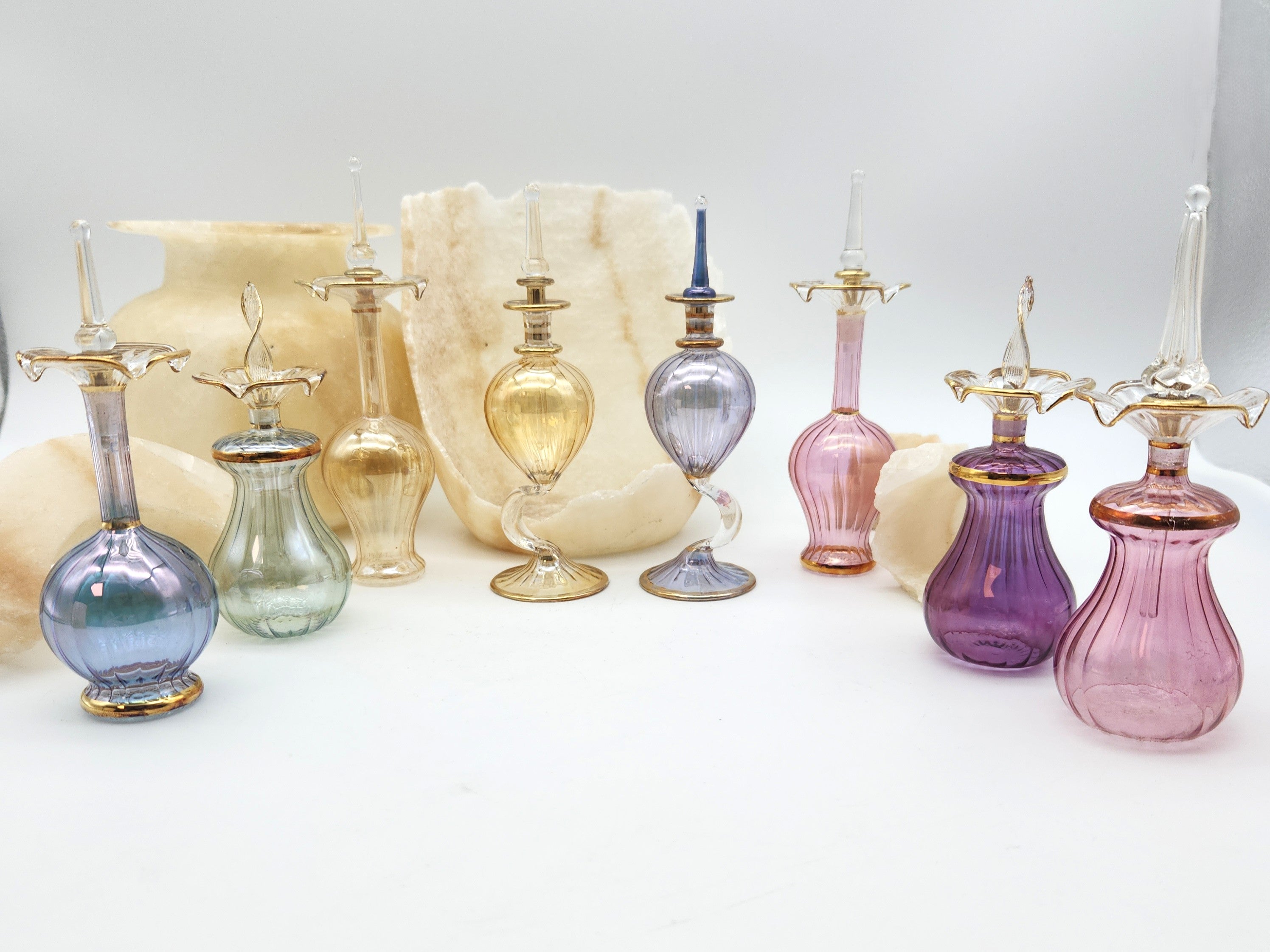 Collection of colorful glass bottles with gold accents on a white background