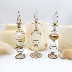 Decorative glass bottles with gold accents on a white background