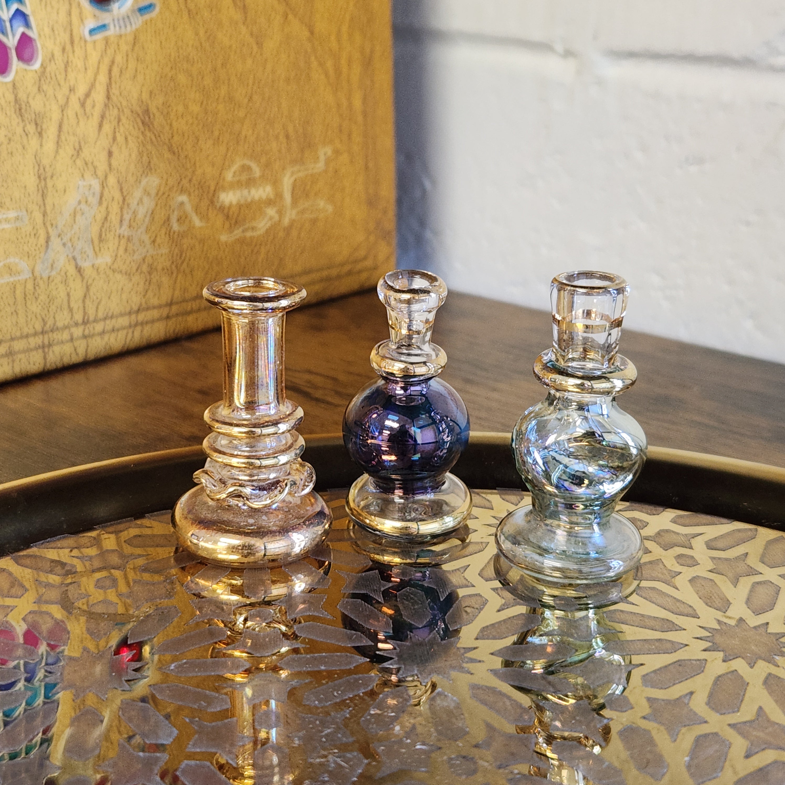 Decorative glass bottles on a wooden surface with a patterned fabric background