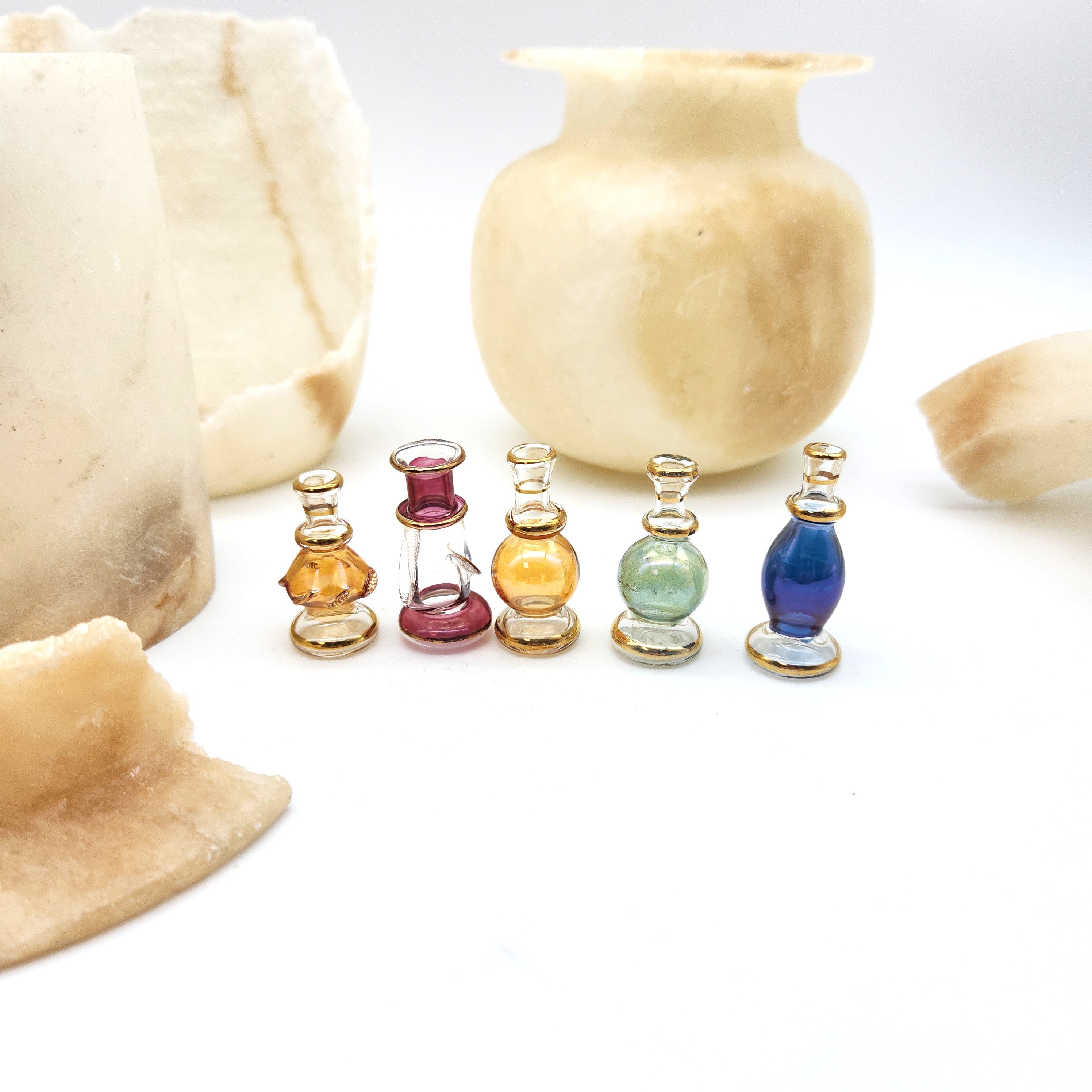 Set of small glass bottles with colorful stoppers on a white background