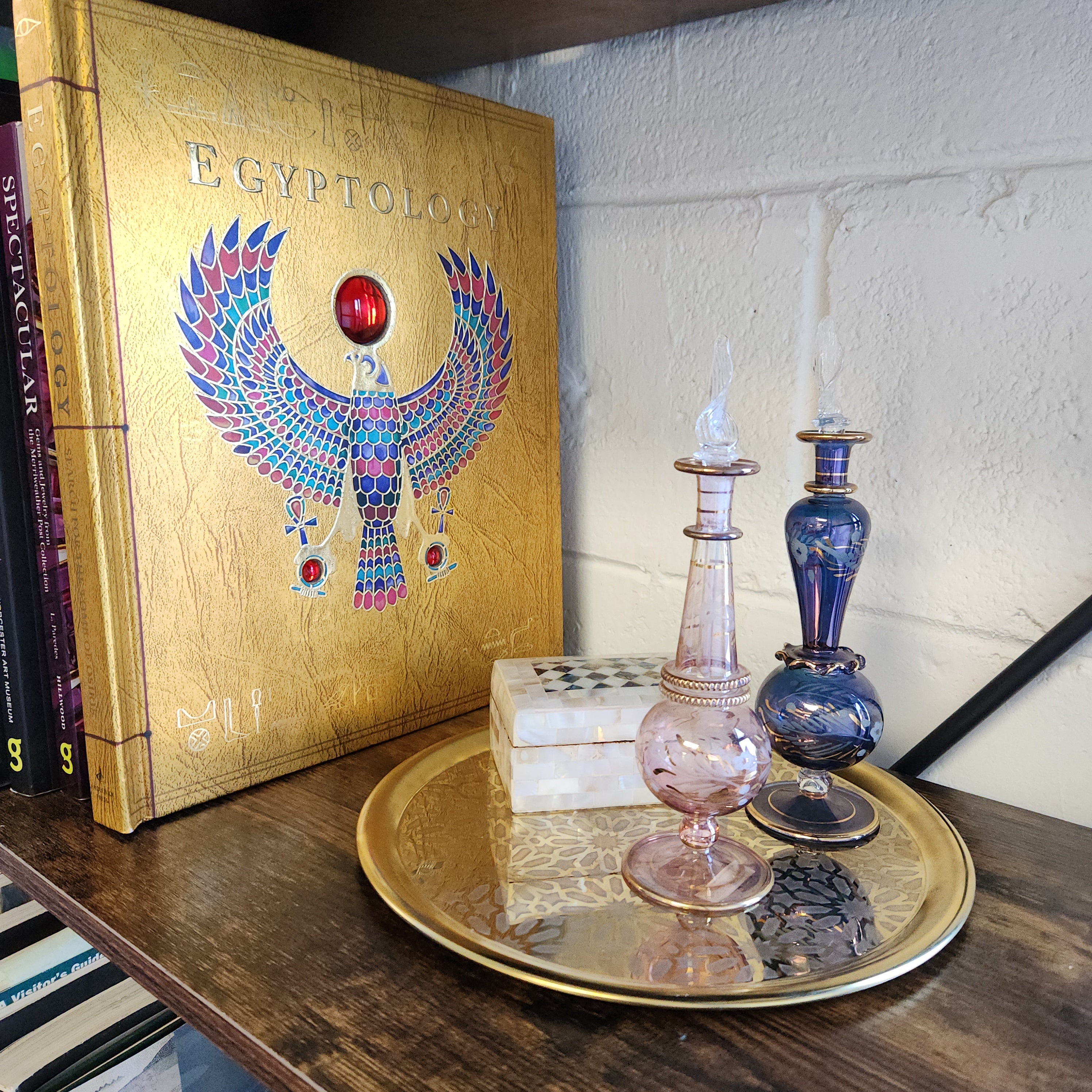 Decorative glass bottles on a stack of books with an Egyptian-themed box.