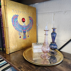 Decorative glass bottles on a stack of books with an Egyptian-themed box.