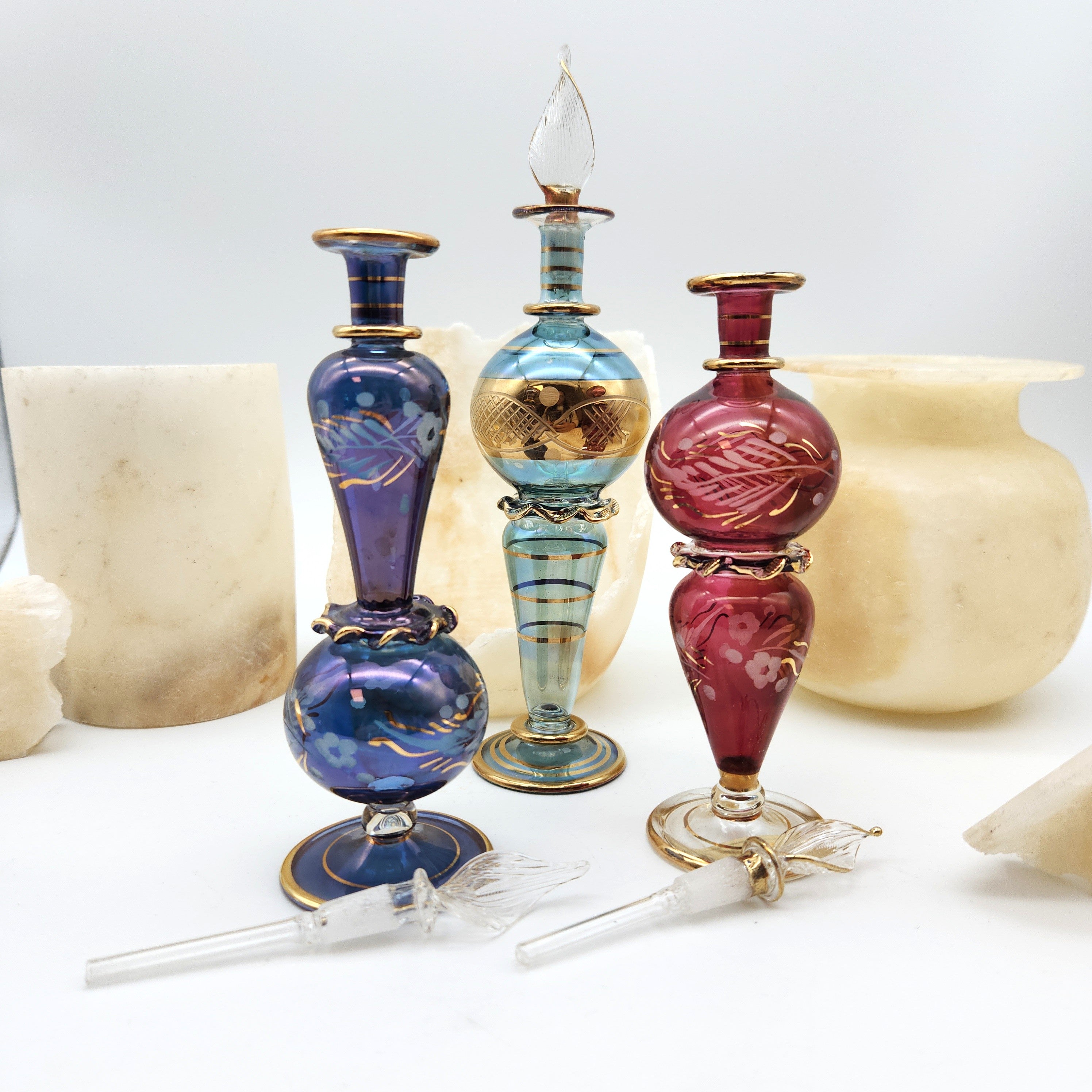Three colorful glass bottles with decorative elements on a white background