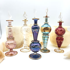 Set of colorful glass perfume bottles with decorative elements on a white background