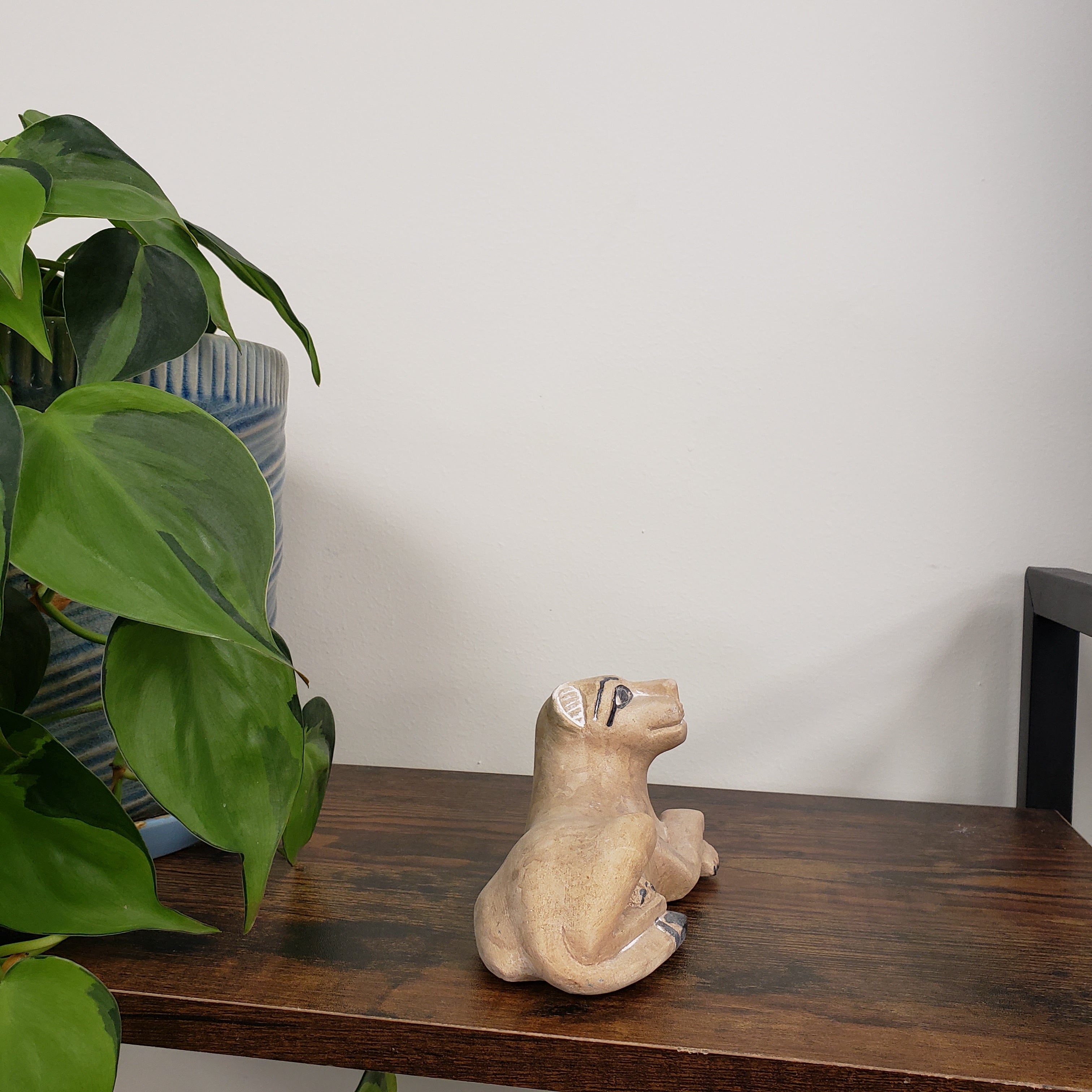 Decorative stone lion head mounted on a wooden board with green plants below.