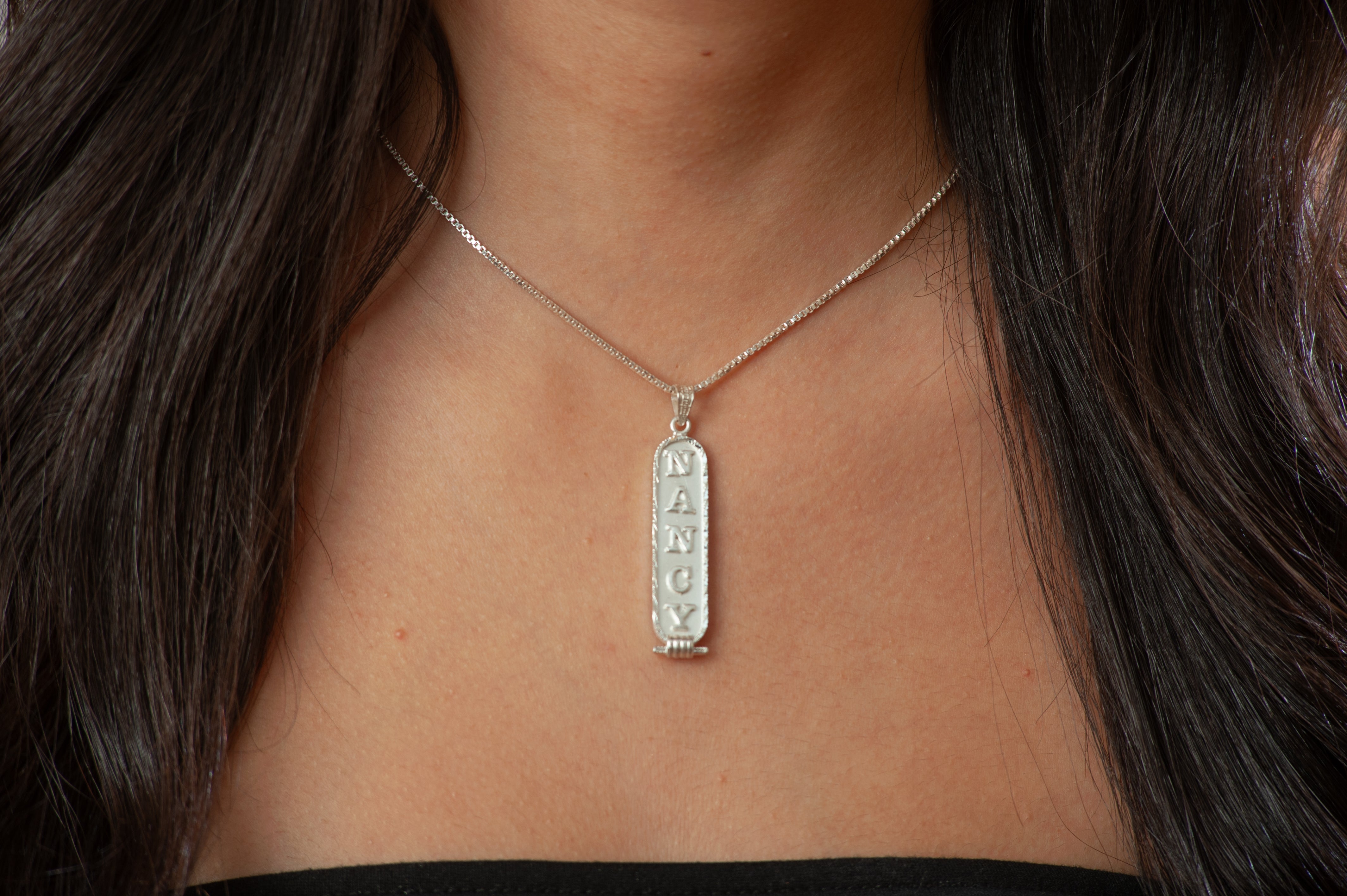 Silver necklace with a pendant on a person's neck