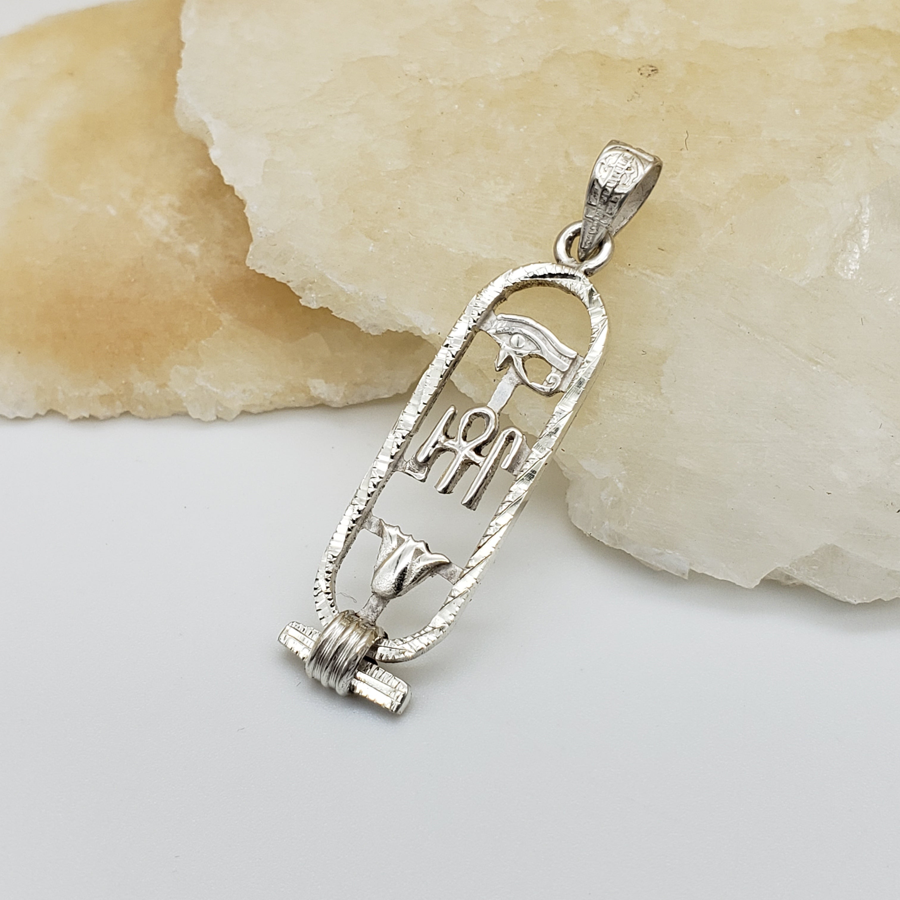 Silver pendant with engraved design on a stone surface