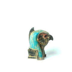 Small figurine of a falcon with turquoise and gold colors on a white background
