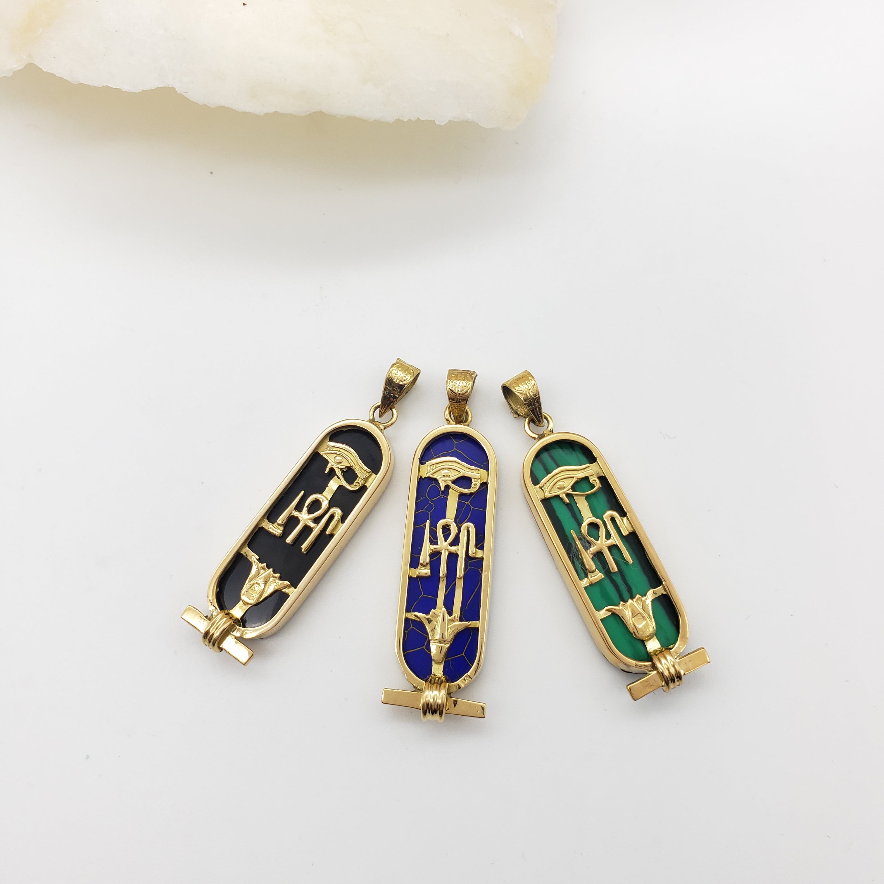 Three decorative gemstone pendants with gold accents on a white background