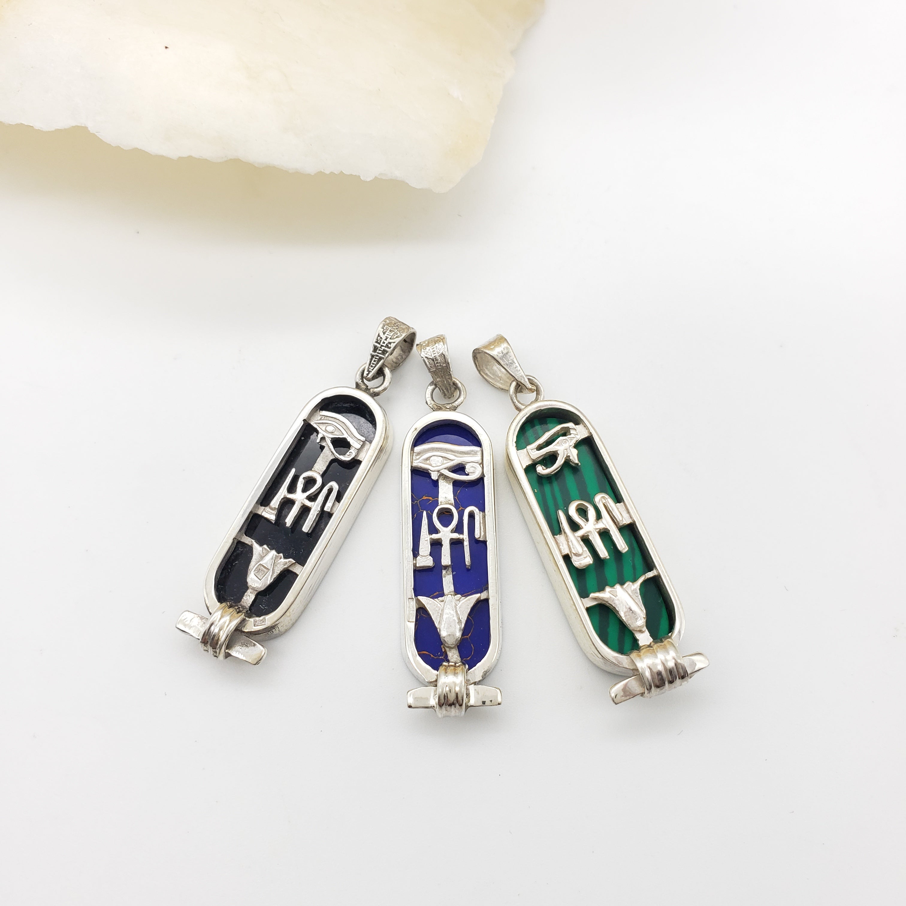 Three decorative pendants with hieroglyphic designs on a white background