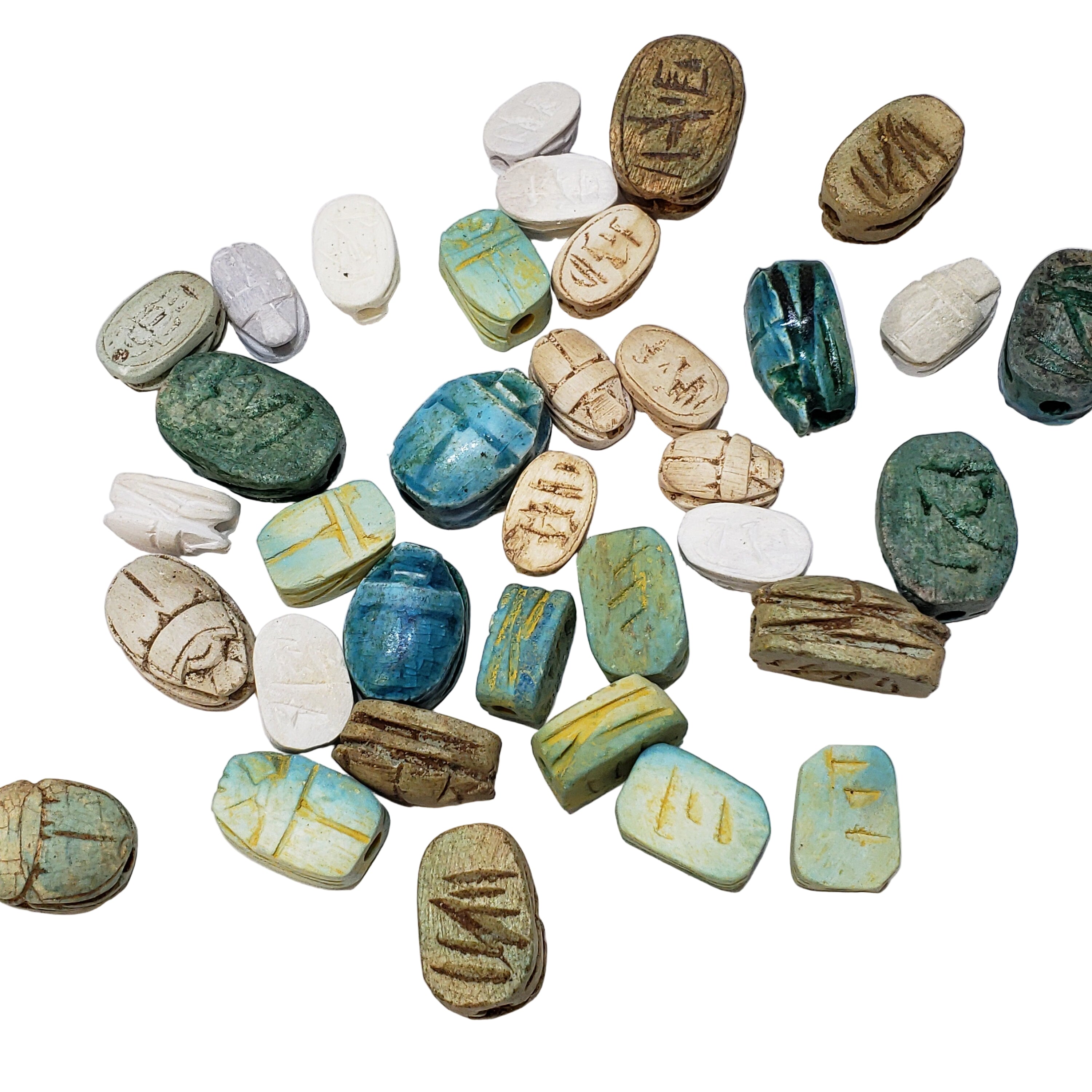 A collection of assorted Egyptian Scarab beads, made of carved soapstone, in various sizes and colors with hieroglyphic symbols on some of them.